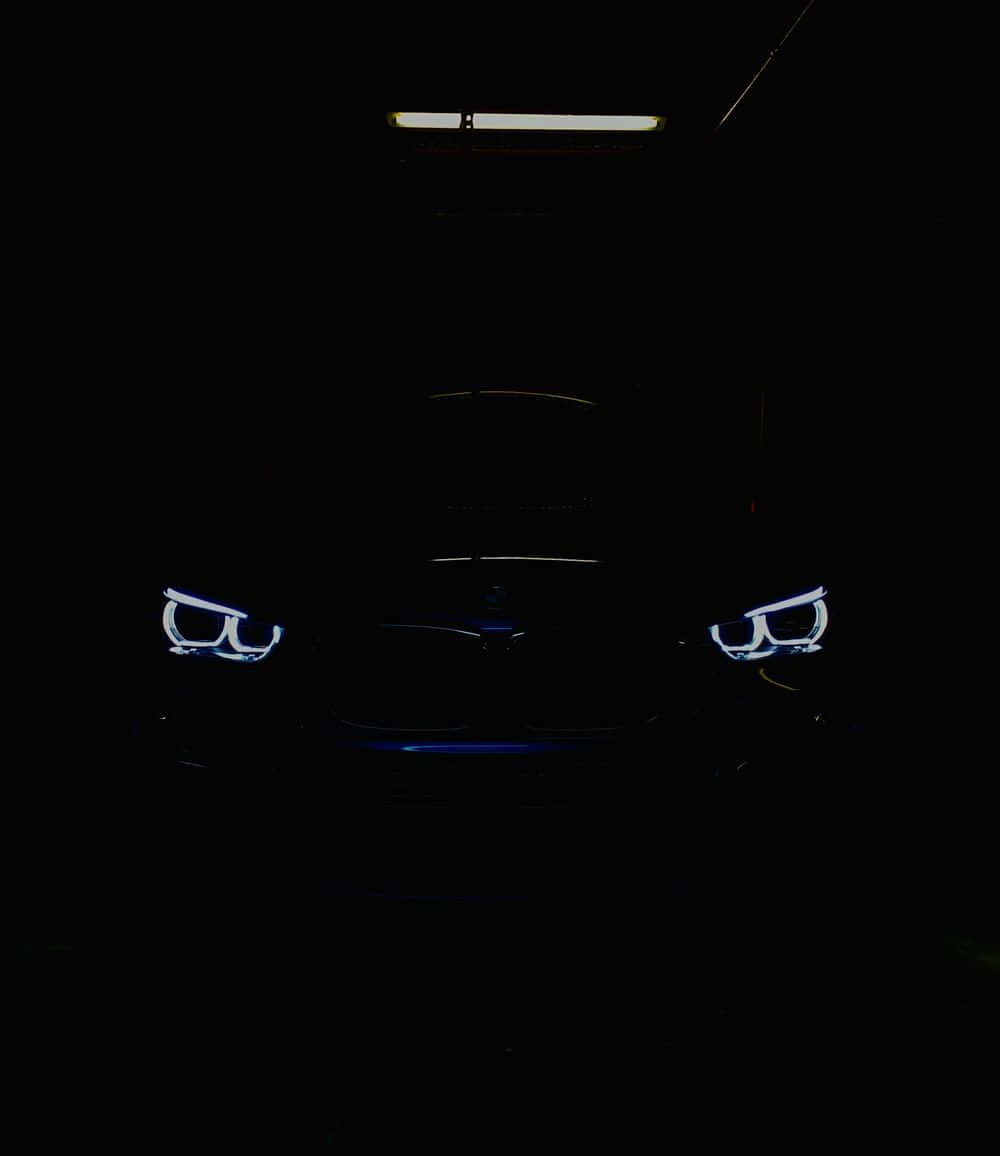 在黑暗車庫中，於一支螢光燈下的一輛汽車的照亮車頭燈。