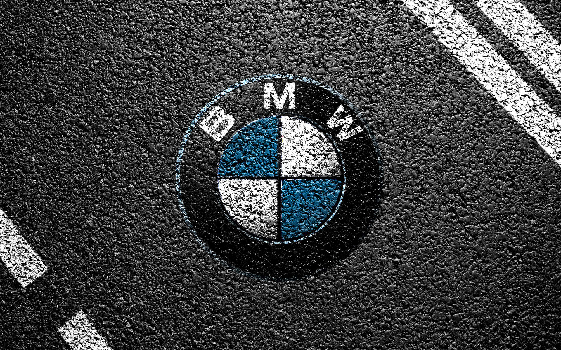 BMW - 高級汽車製造商標誌 壁紙 — 一個風化的BMW標誌畫在粗糙的瀝青上，附近有白色道路標線彎曲。