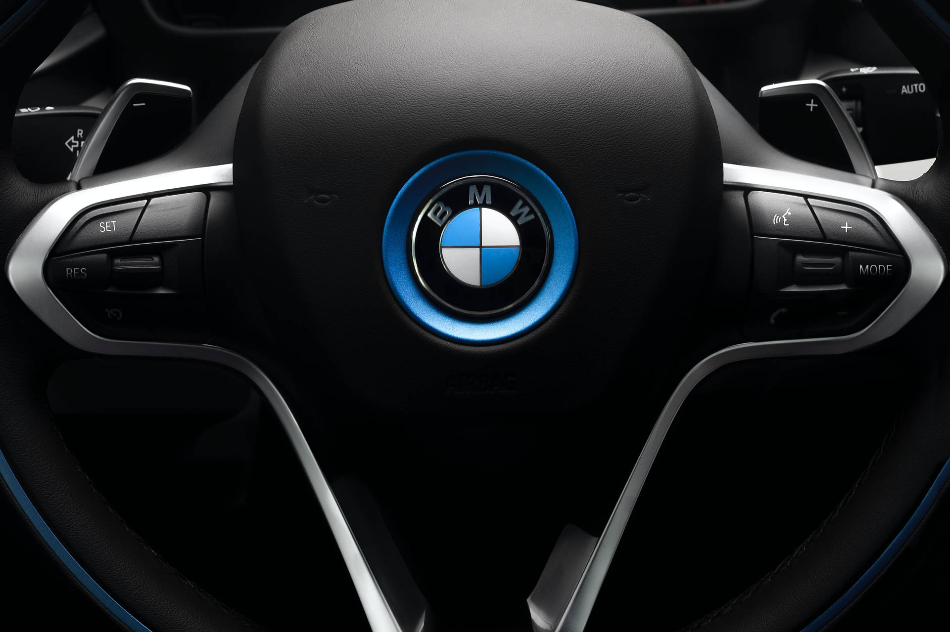 BMW i8 方向盤，帶有藍色發光標誌和控制按鈕。