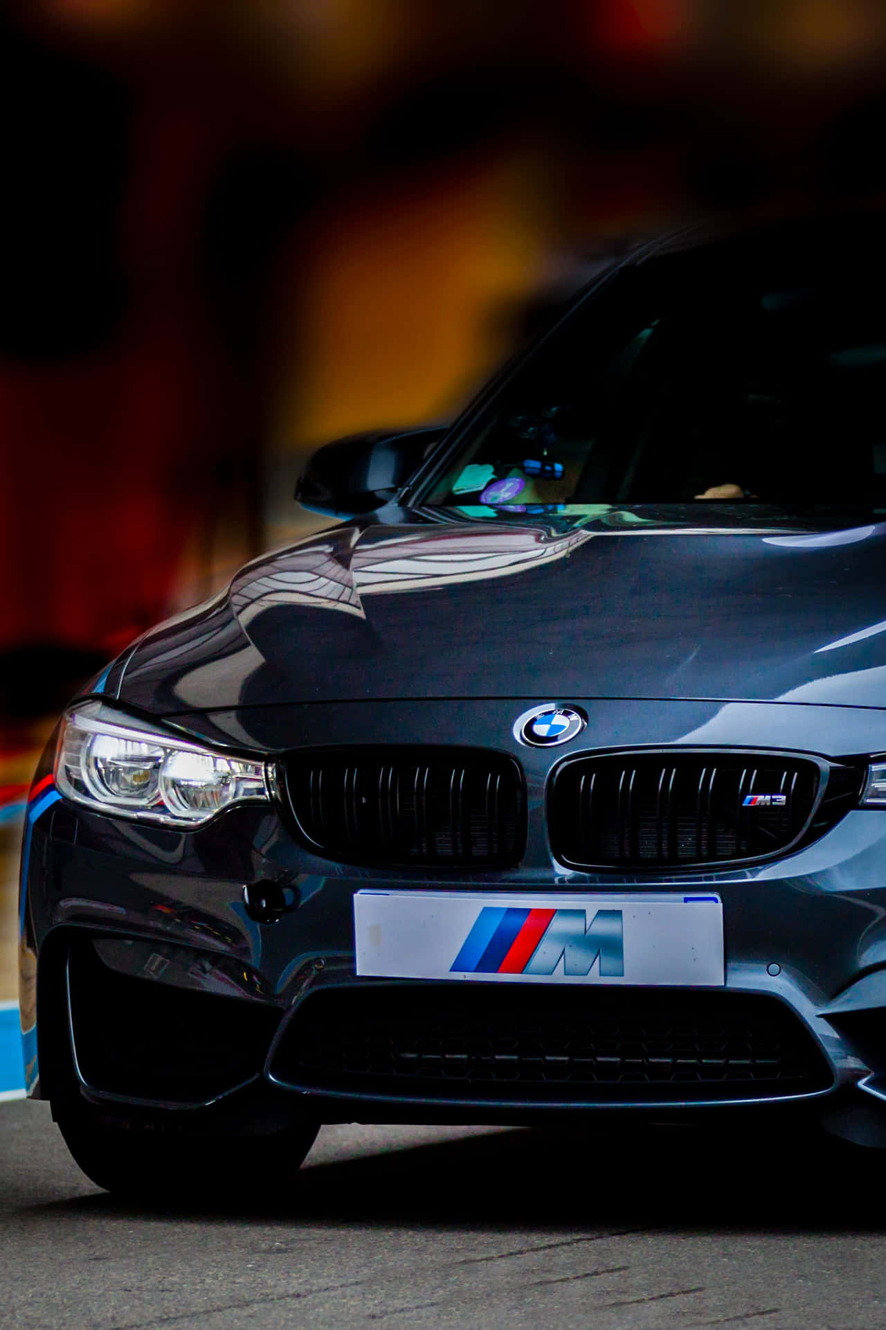 夜晚街道上黑色BMW M汽車，車頭燈亮起。