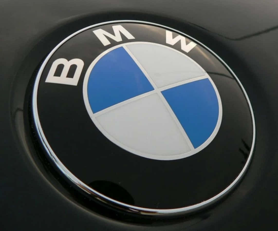 BMW徽章標誌 壁紙 — 黑色汽車表面上帶有藍白四象限的光澤BMW標誌特寫。