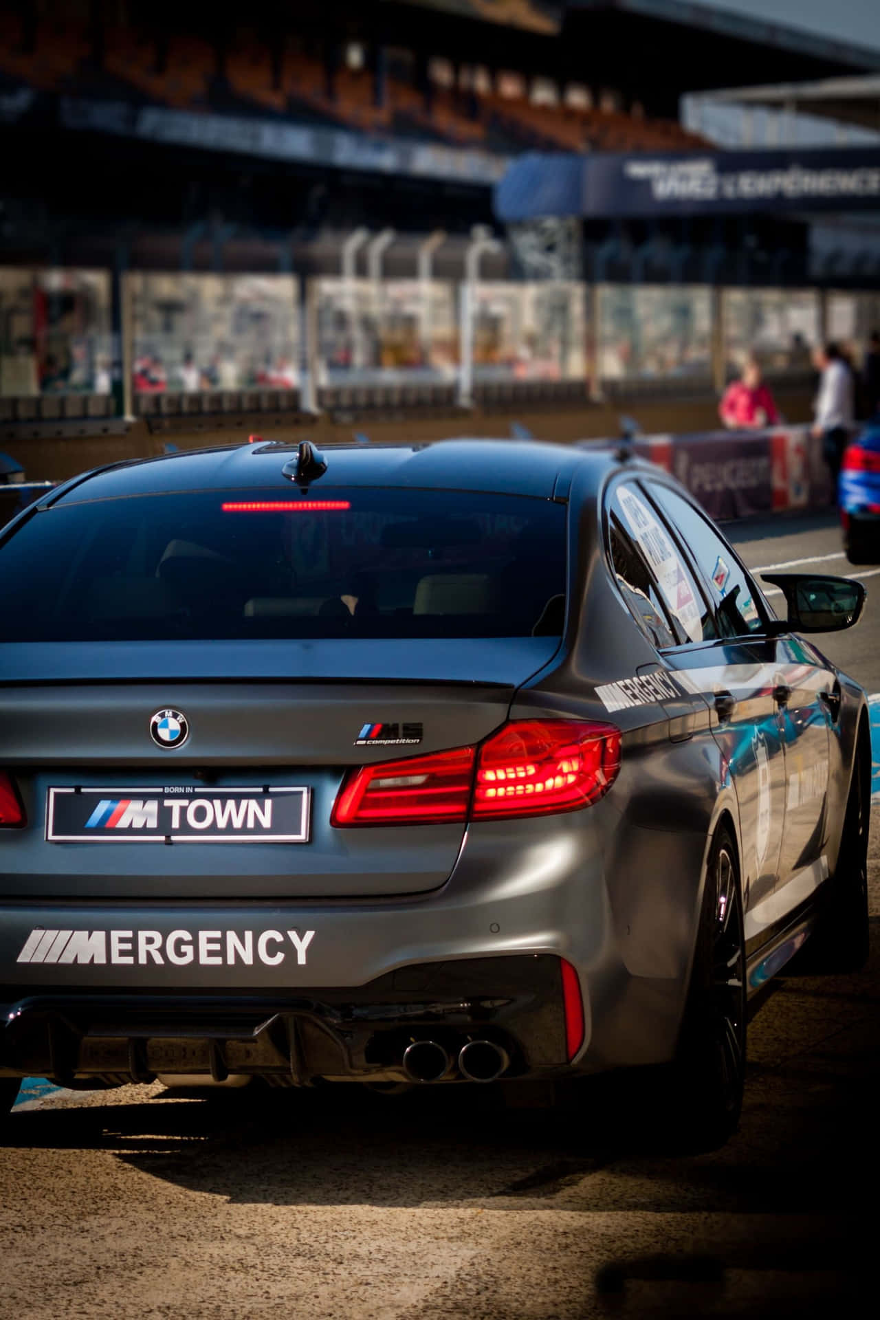 啞光灰色BMW M5賽車，帶有定制貼紙，在暮色中的賽道上。