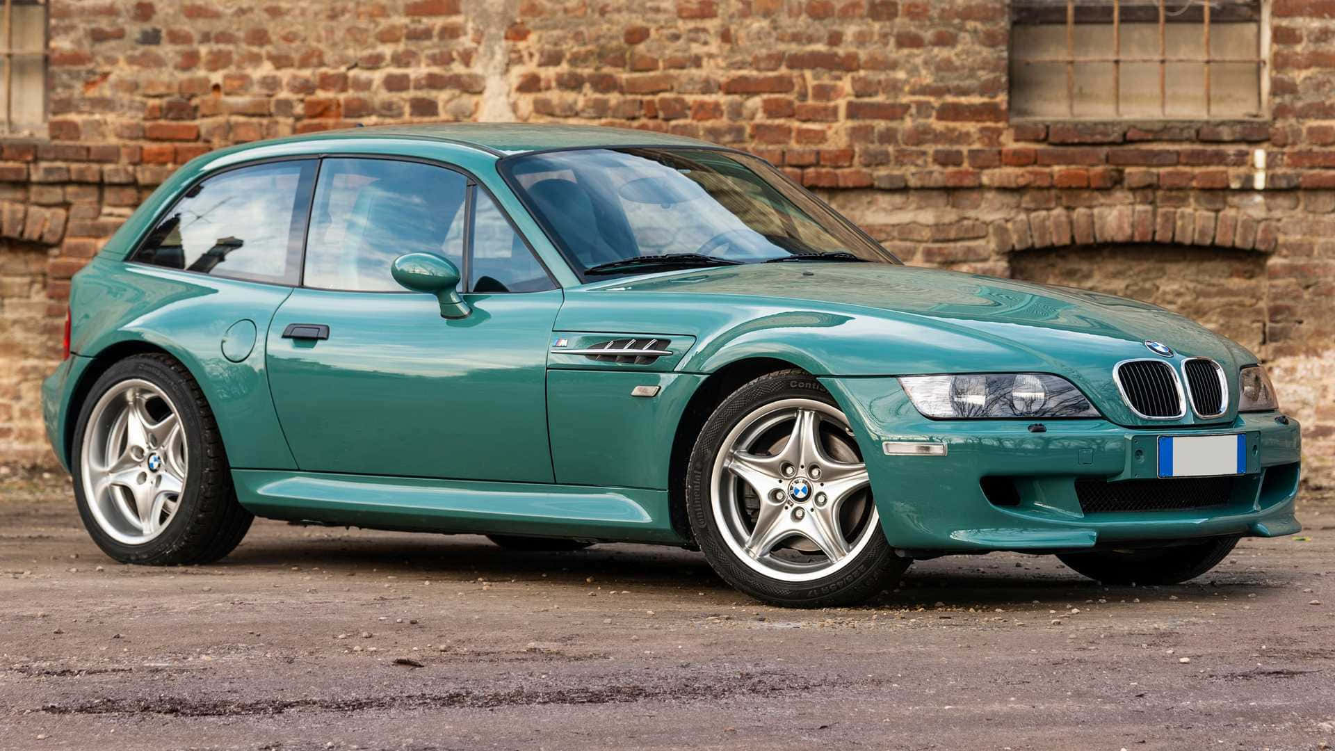 BMW賽車蓄勢待發 壁紙 — 一架時尚嘅青綠色BMW Z3跑車停泊喺風化嘅磚牆前面，牆上有個鄉村風格嘅窗。