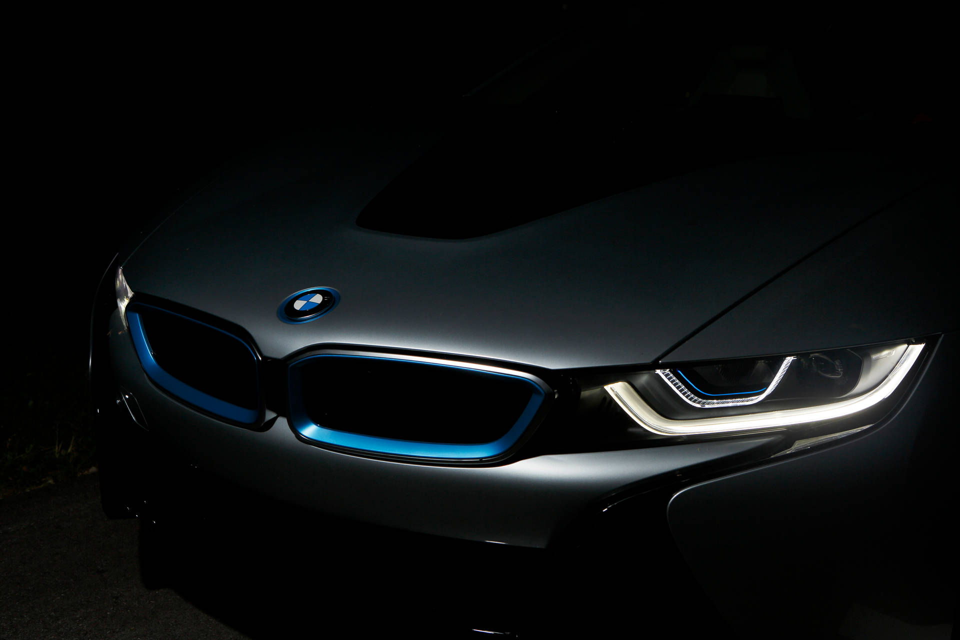 黑色BMW i8在黑暗中帶有發光藍色飾條和頭燈的特寫。