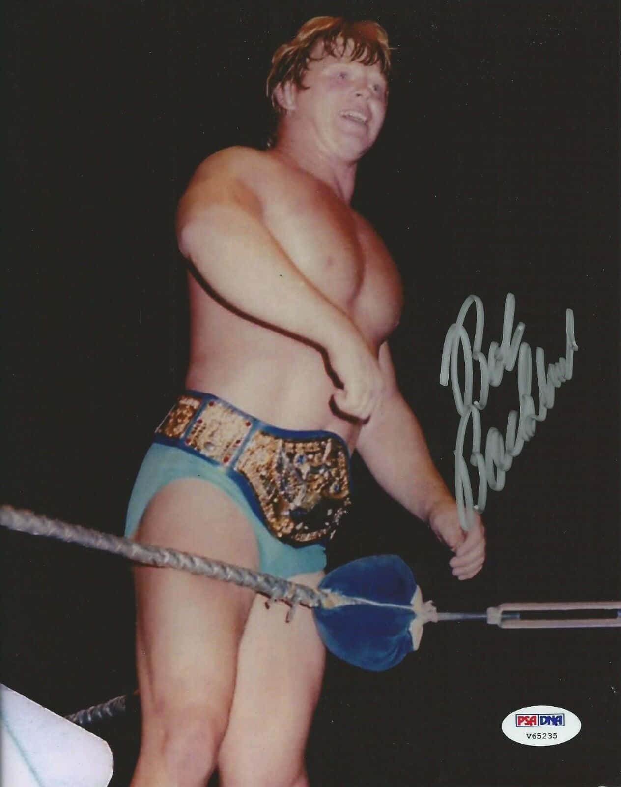 摔角手 Bob Backlund 在擂台上手持藍色狼牙棒和冠軍腰帶的簽名照片。