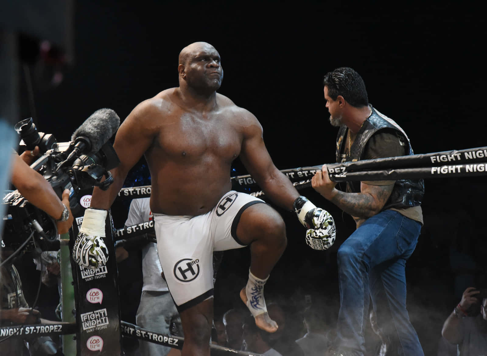 Bob Sapp 擊戰姿勢 壁紙 — 一位肌肉發達的拳擊手穿著白色短褲站在拳擊台上，他的教練在 Fight Night 賽事前穩定他。