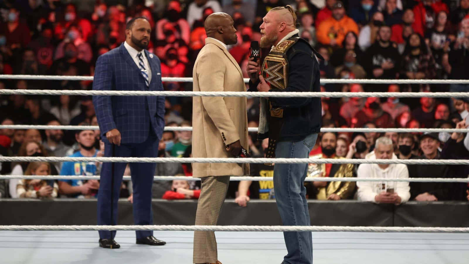Bobby Lashley 與 Brock Lesnar 面對面 壁紙 — 三名摔角手在擂台上對峙，繩索後有歡呼的人群，背景是明亮的場館燈光。