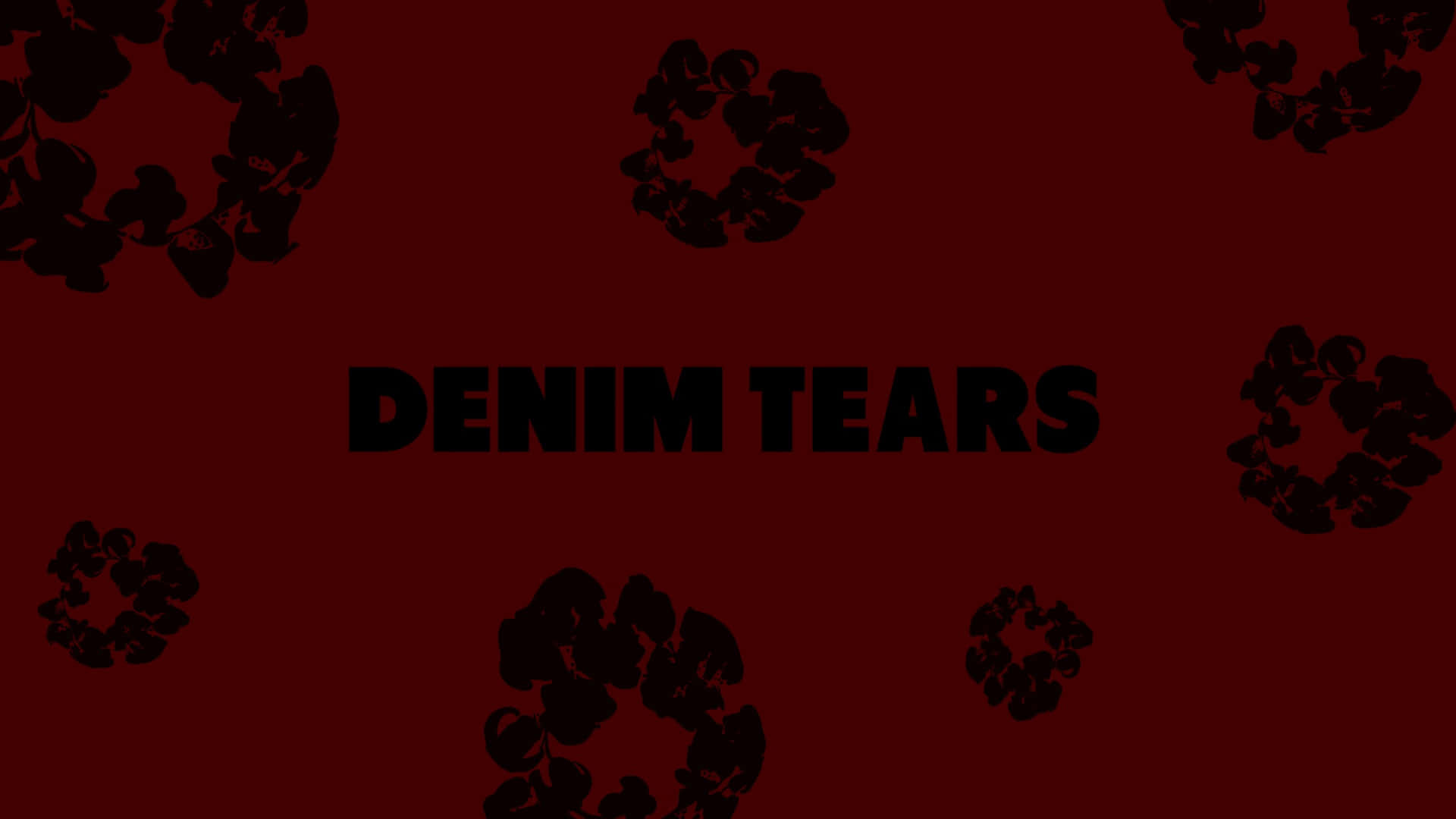  壁紙 — 粗體黑色文字 DENIM TEARS 居中於深紅色背景上，並帶有散落的黑色牛仔布撕裂剪影。