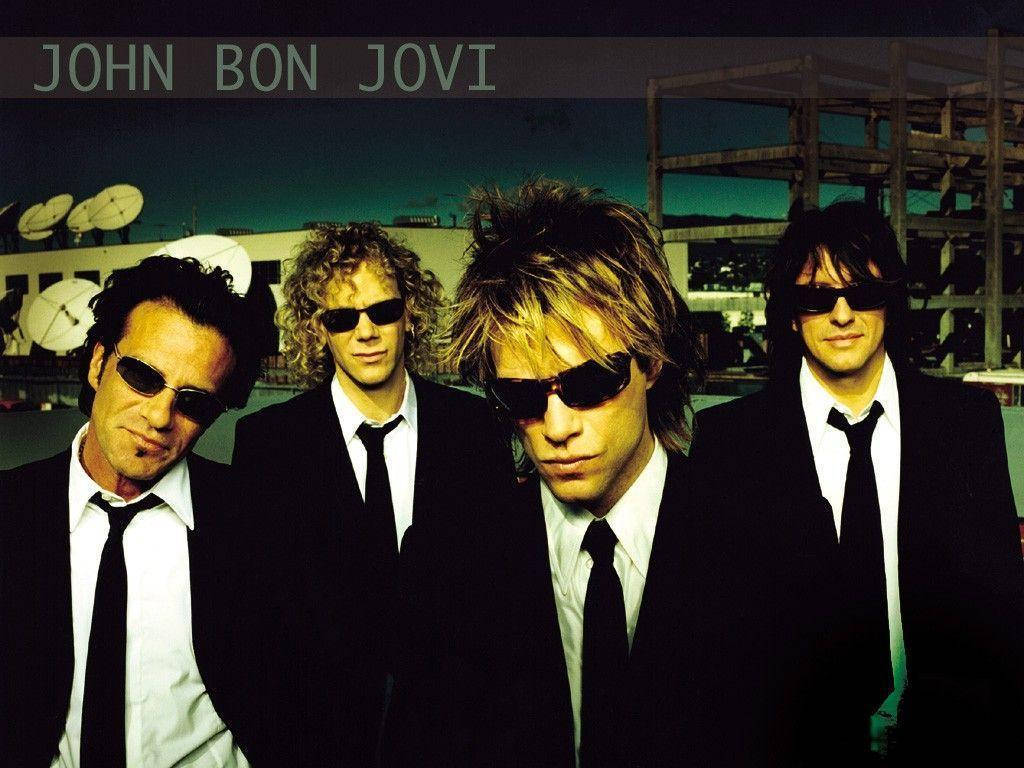 John Bon Jovi 和樂團成員在黃昏時穿著黑色西裝和太陽眼鏡。