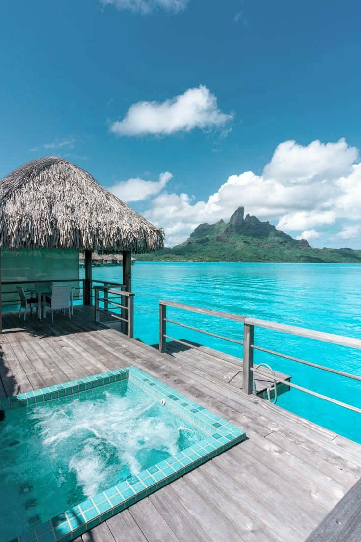 水上甲板，按摩浴缸面向碧綠色潟湖和山脈背景。