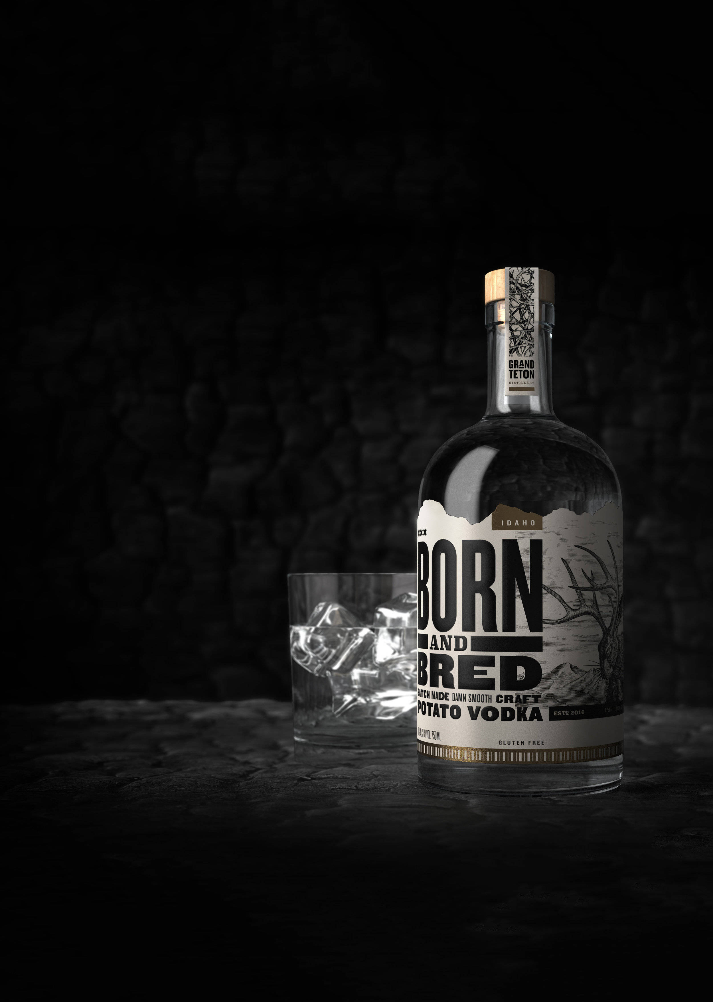 Born And Bred伏特加配冰塊玻璃杯 壁紙 — 一瓶時尚的Born and Bred馬鈴薯伏特加放在深色紋理表面上，旁邊有一杯冰塊，背景是黑色石牆。