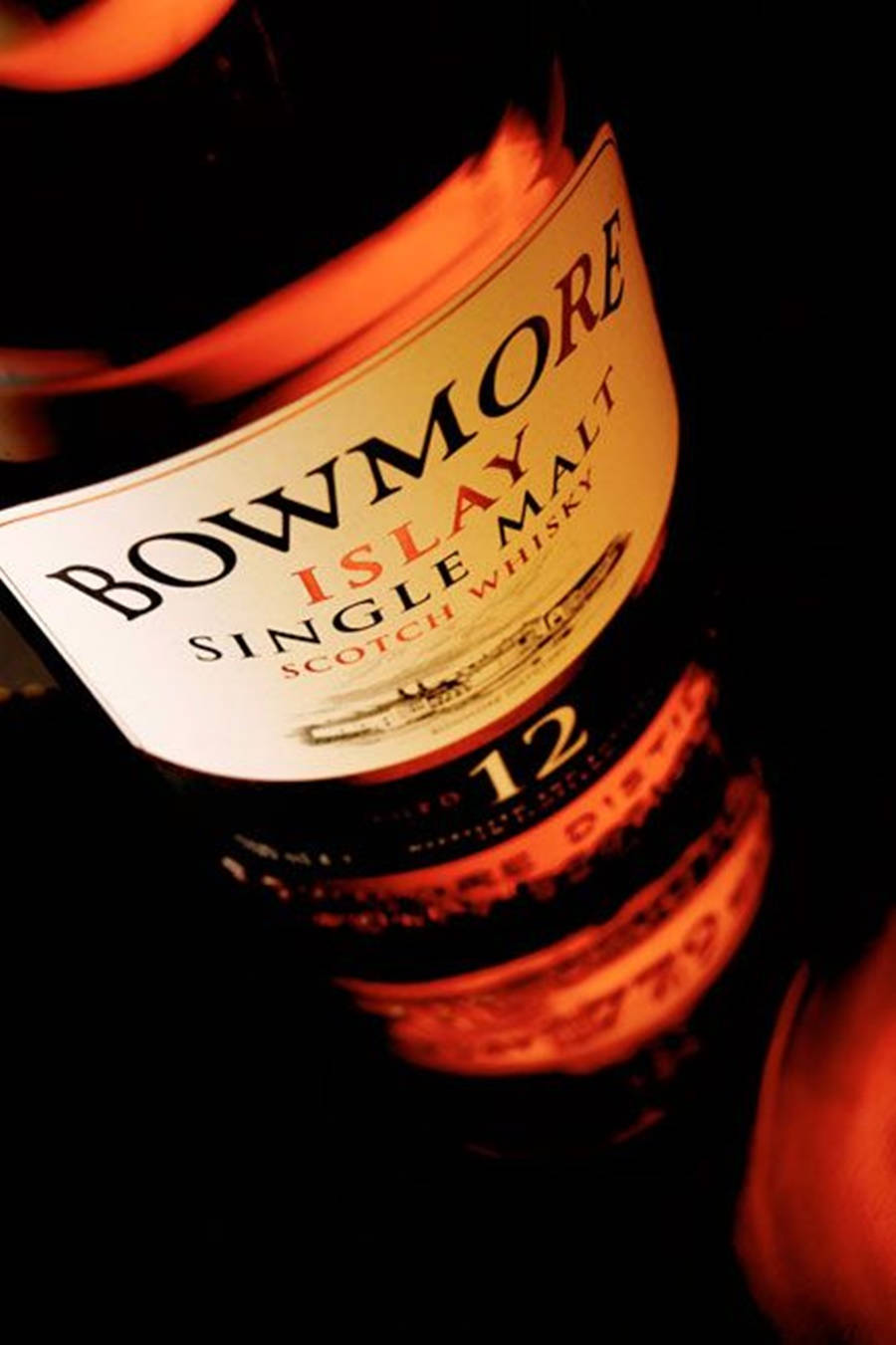 在黑色背景下，溫暖橙色光線中閃耀的 Bowmore 威士忌酒瓶標籤。
