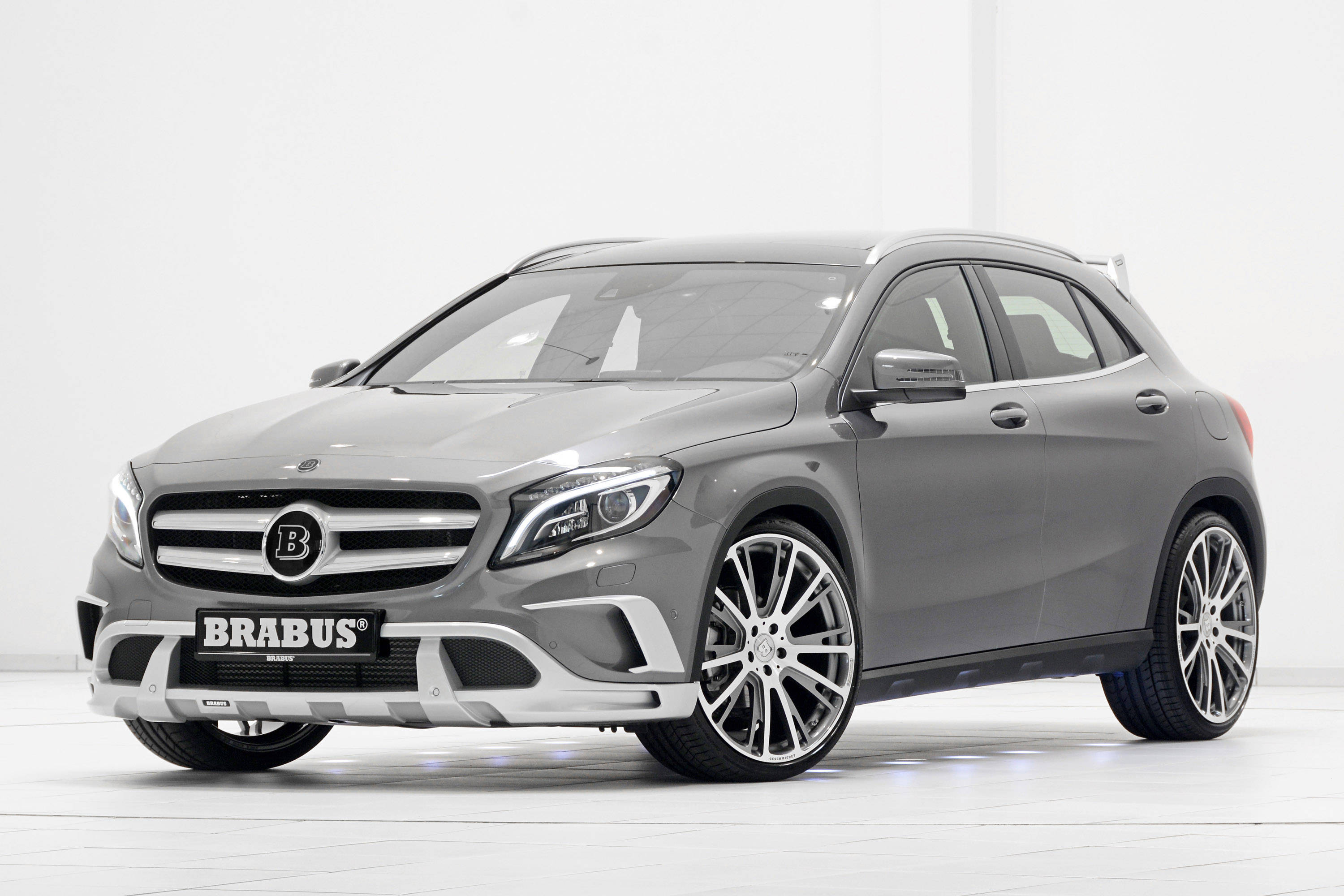 Brabus調校的梅賽德斯-奔馳SUV 壁紙 — 一輛時尚的灰色Brabus改裝Mercedes GLA-Class SUV，配備定制合金輪圈和侵略性前保險桿，在明亮的白色工作室中拍攝。