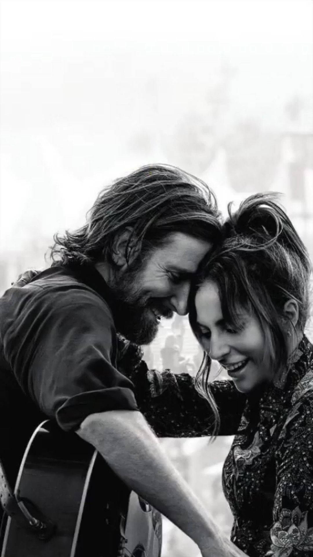 Bradley Cooper 與 Lady Gaga 擁抱 壁紙 — 一對微笑情侶與結他分享溫柔時刻的黑白親密肖像。