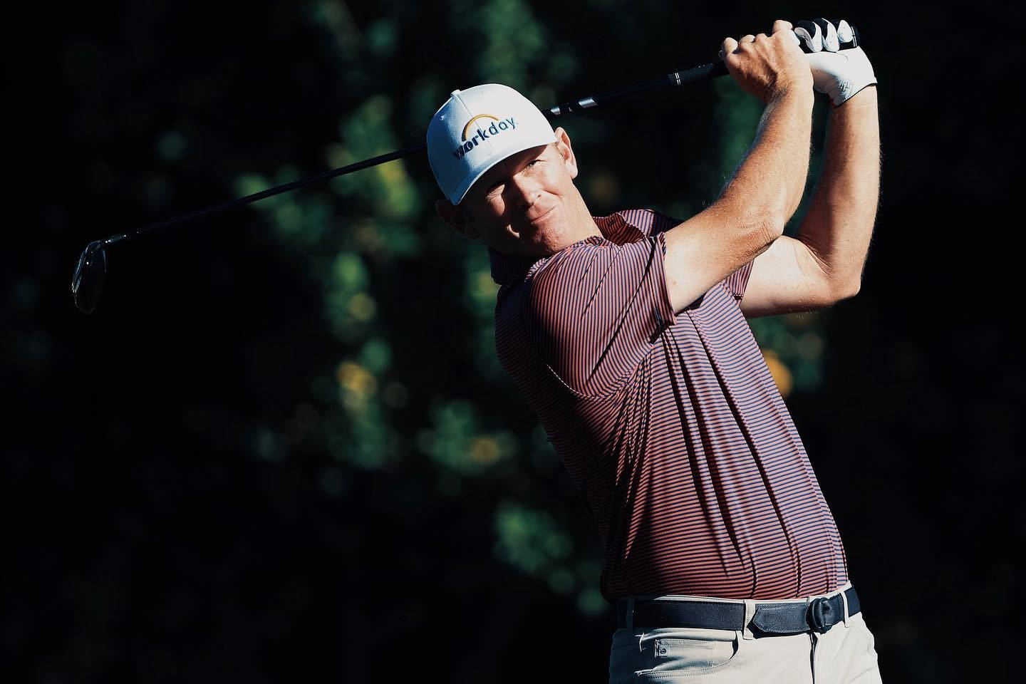 Brandt Snedeker 全神貫注 壁紙 — 一名高爾夫球手正在揮桿，表情專注，背景是模糊的暗色森林。