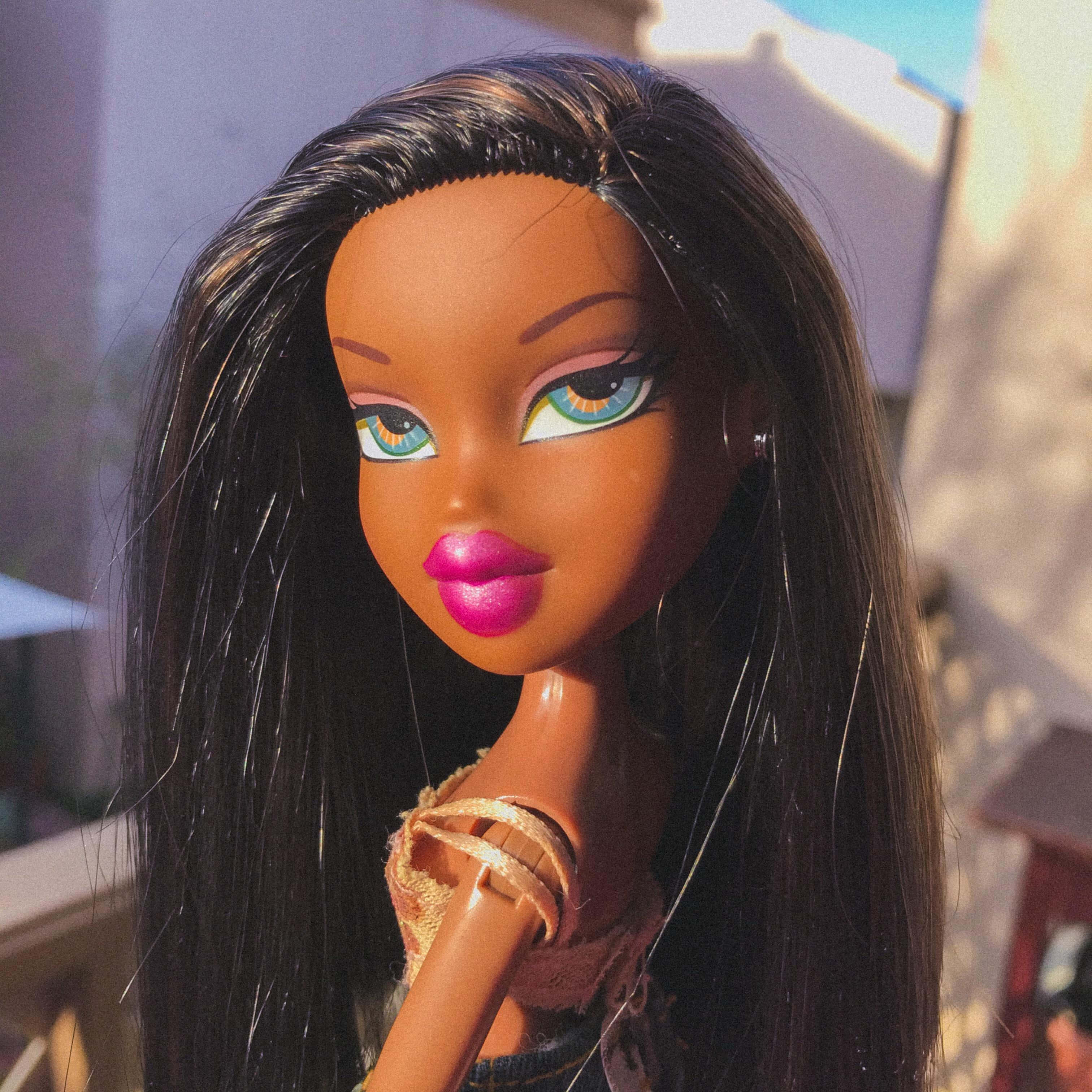 Bratz美學，充滿活力的氛圍！ 壁紙 — Bratz 公仔嘅特寫，長長嘅黑髮、鮮粉紅色嘴唇同搶眼嘅藍色眼睛，沐浴喺溫暖嘅陽光下。