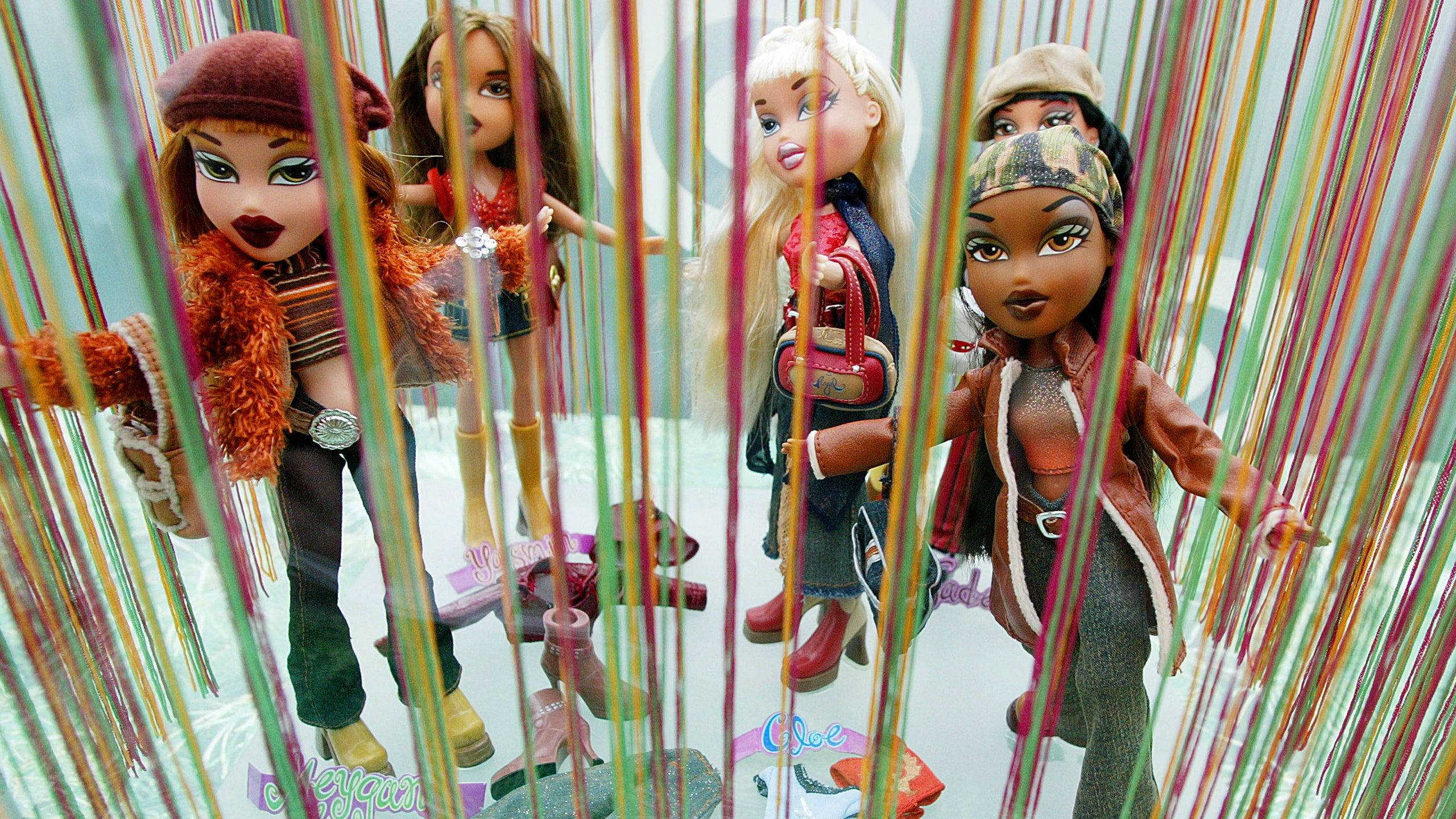 Bratz娃娃被鎖住 壁紙 — 五個穿著時尚服裝的 Bratz 公仔站在色彩繽紛的懸掛線簾後面，呈現出有趣的展示。