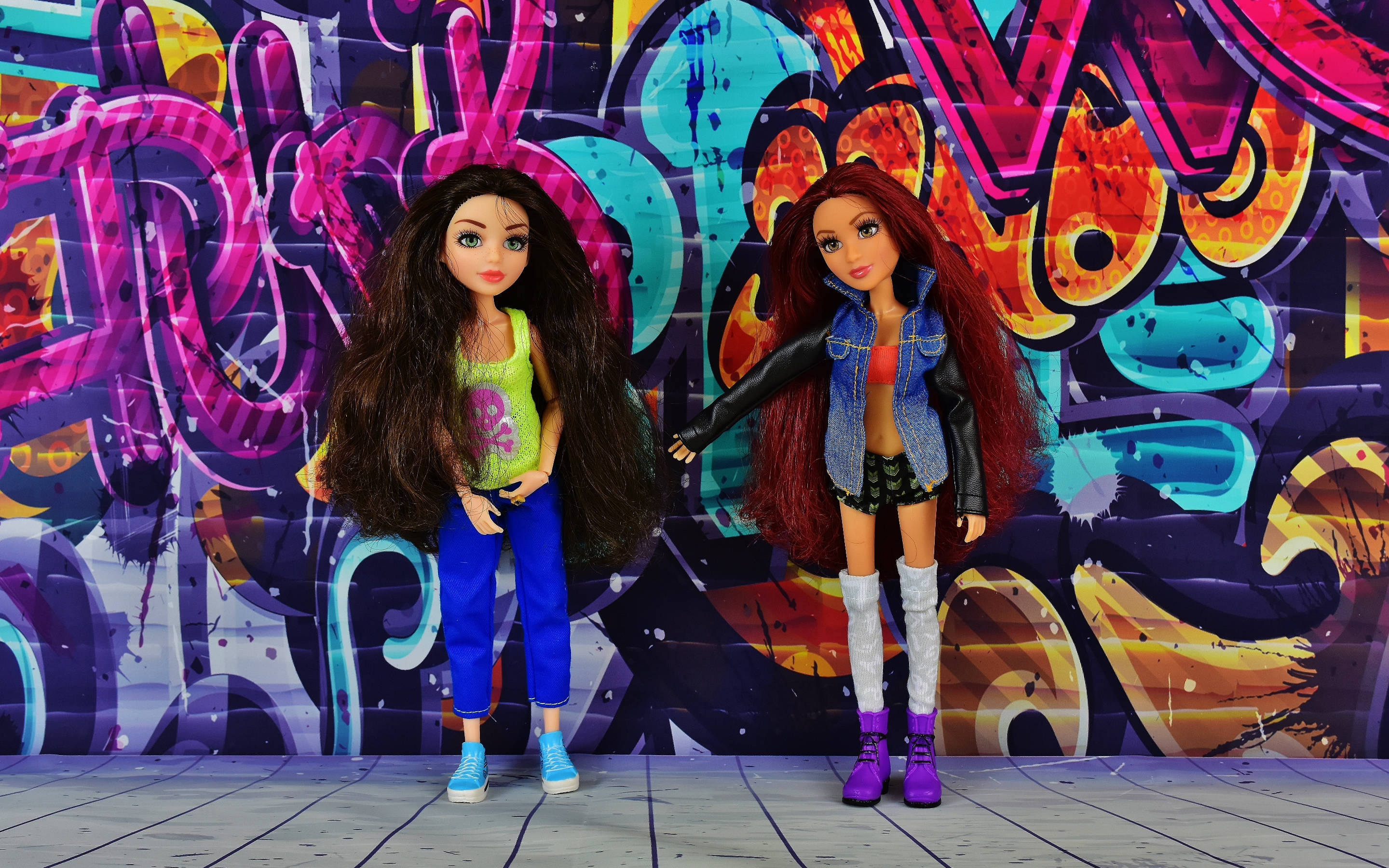 Bratz玩偶塗鴉牆 壁紙 — 兩個時尚公仔喺充滿霓虹色彩同大膽風格字體嘅鮮豔塗鴉牆前自信地擺姿勢。