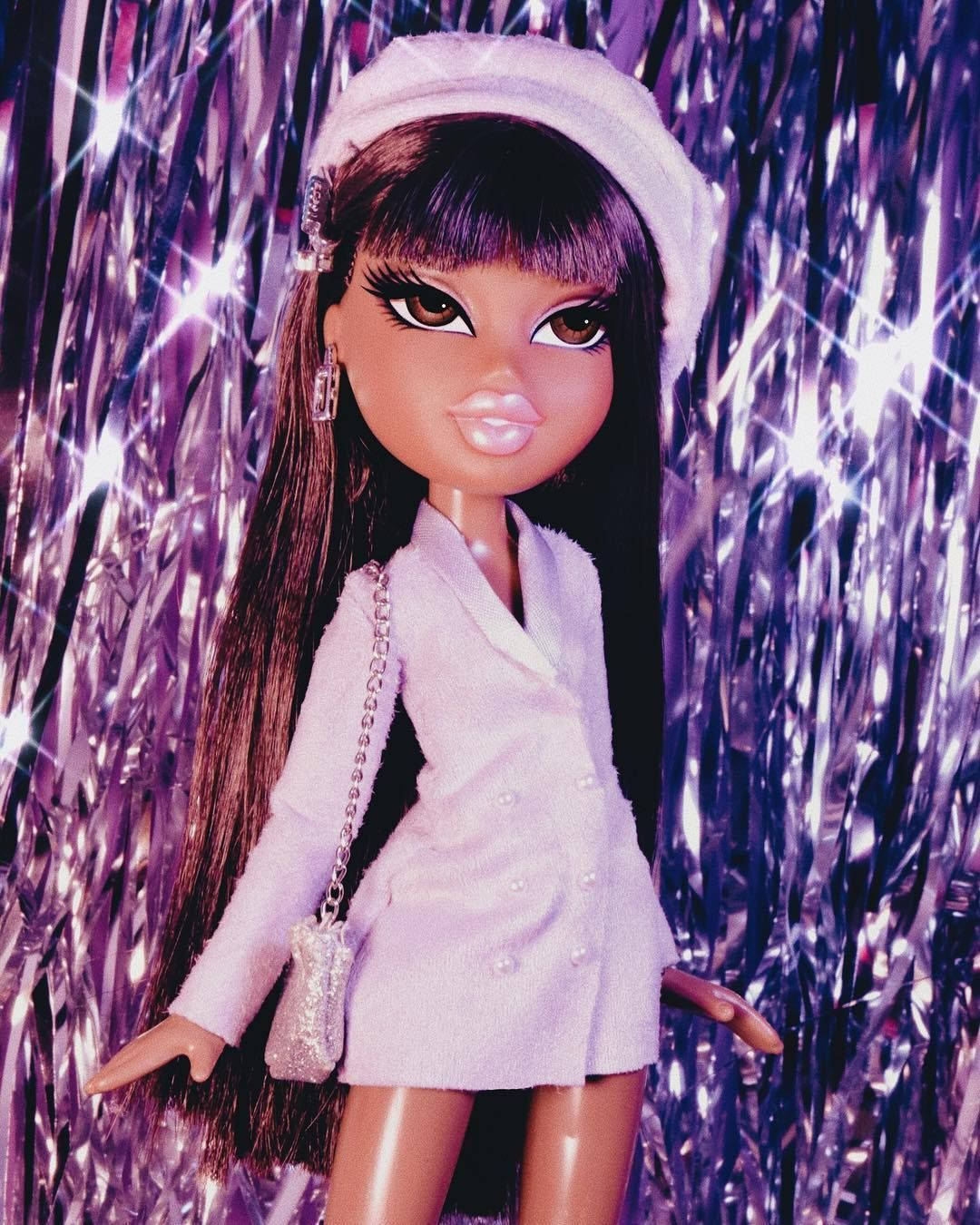 Bratz莎夏閃亮窗簾 壁紙 — 一個長長深色頭髮、戴白色貝雷帽的娃娃自信地站在閃閃發光的紫色閃粉背景前。