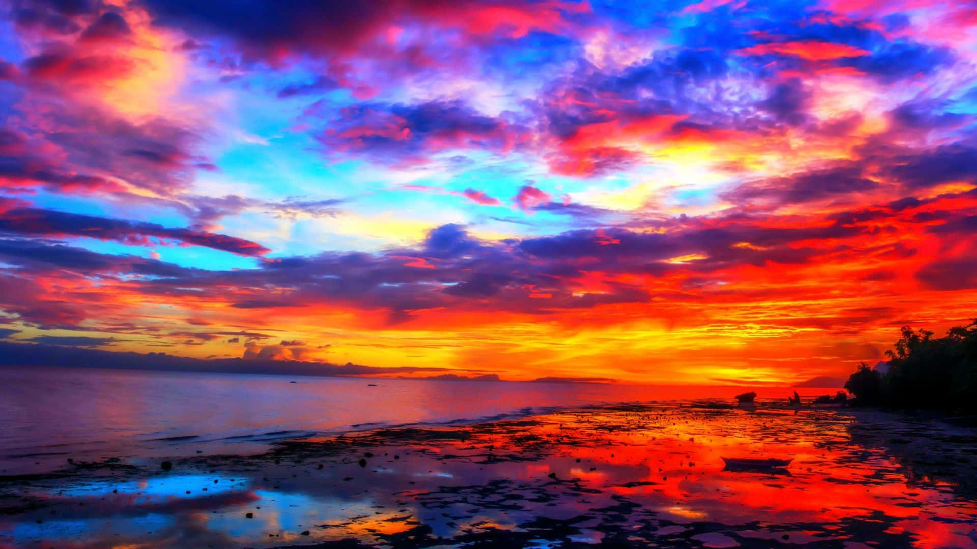 Colorful Sunset 桌布 壁紙 — 令人驚嘆的日落用火熱的橙色和深紫色描繪天空，倒映在平靜的海水中。