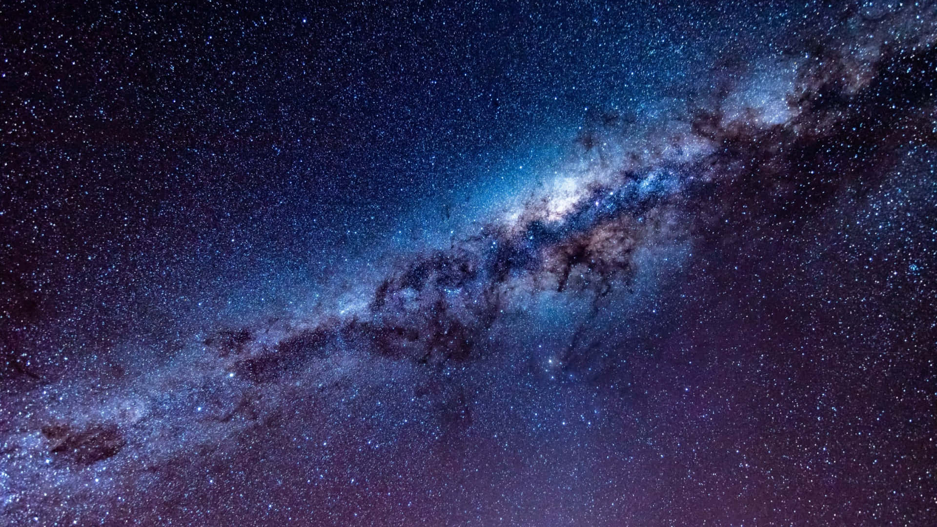  壁紙 — 令人嘆為觀止的銀河系景觀，在繁星點點的夜空中散發出藍色和紫色的光芒。