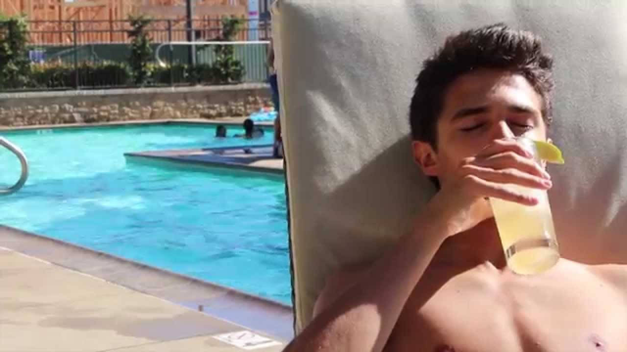 Brent Rivera 泳池邊飲檸檬汁照 壁紙 — 一名年輕男子赤裸上身，在泳池邊的躺椅上放鬆，在明媚陽光下啜飲檸檬水。