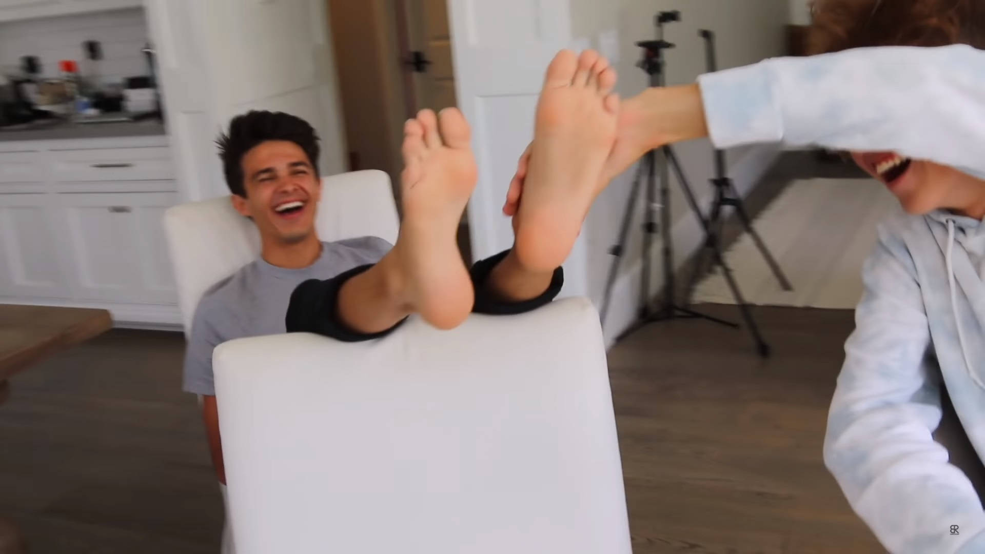 Brent Rivera 腳部被逗笑照 壁紙 — 兩個人在明亮的現代家居中歡笑，其中一人頑皮地握住另一人的赤腳。