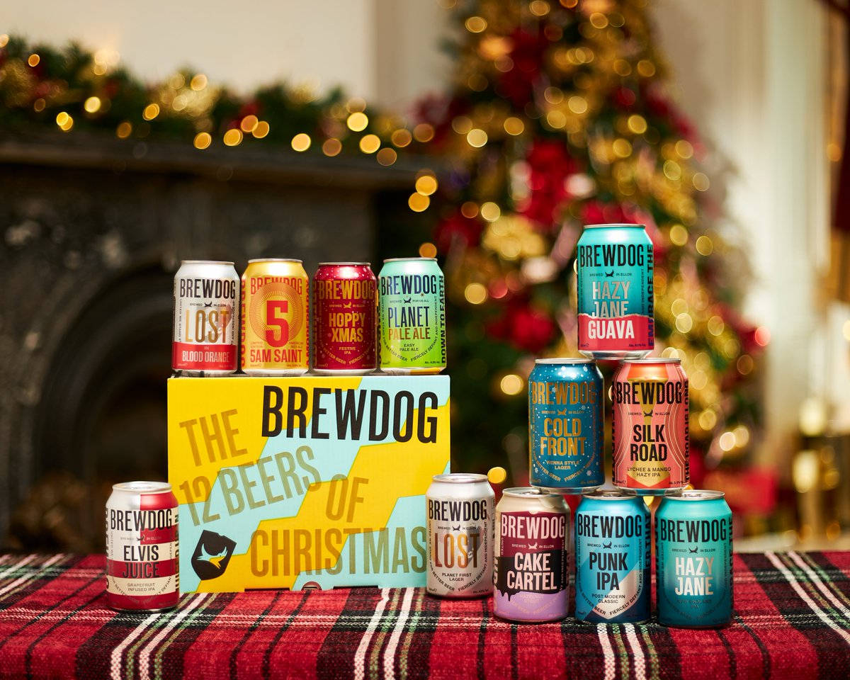 BrewDog 12 Beers Of Christmas 包裝 壁紙 — BrewDog 的 12 Beers of Christmas 罐裝啤酒在裝飾好的聖誕樹和壁爐前的格子毯上擺放的節日展示。