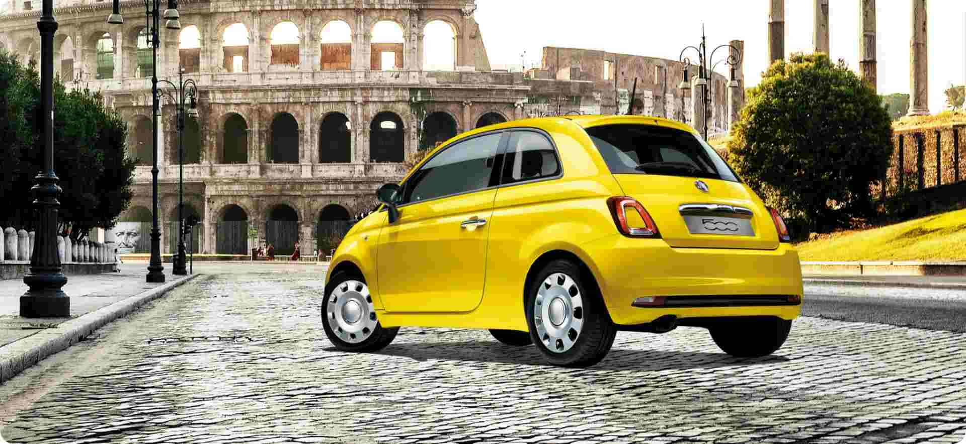 Fiat 500 桌布 壁紙 — 一輛亮黃色的菲亞特500停在鵝卵石街道上，背景是羅馬競技場。