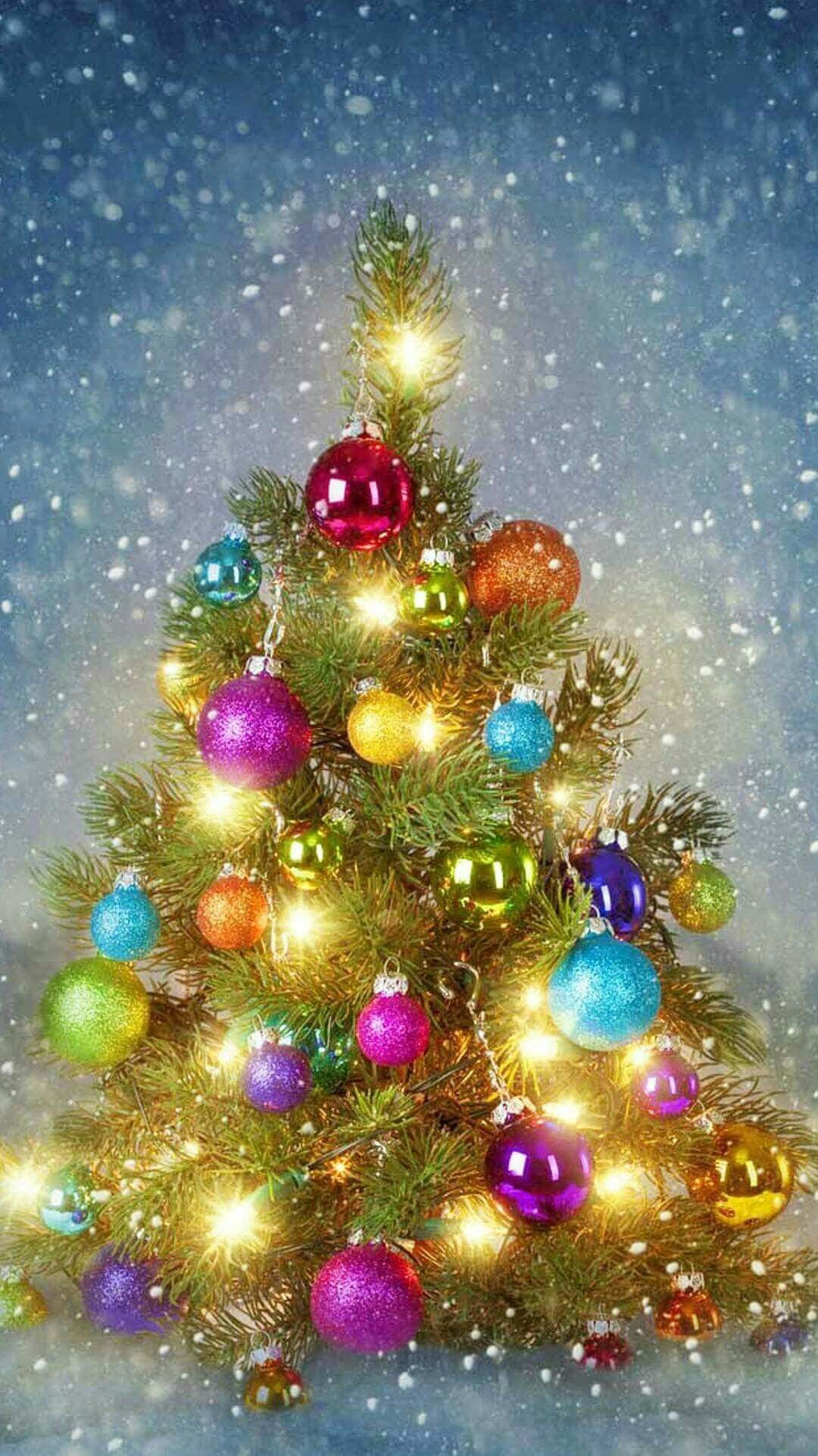 Vintage Christmas 桌布 壁紙 — 一棵明亮照明的聖誕樹，裝飾著色彩繽紛閃亮的飾物，矗立在雪白的藍天下，雪花輕輕飄落。