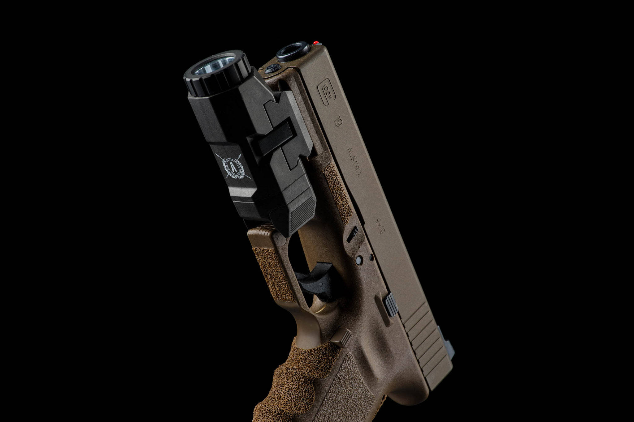 銅色Glock 19 壁紙 — 一支棕黑色戰術手槍，裝有燈光和激光，傾斜放置在純黑色背景上。