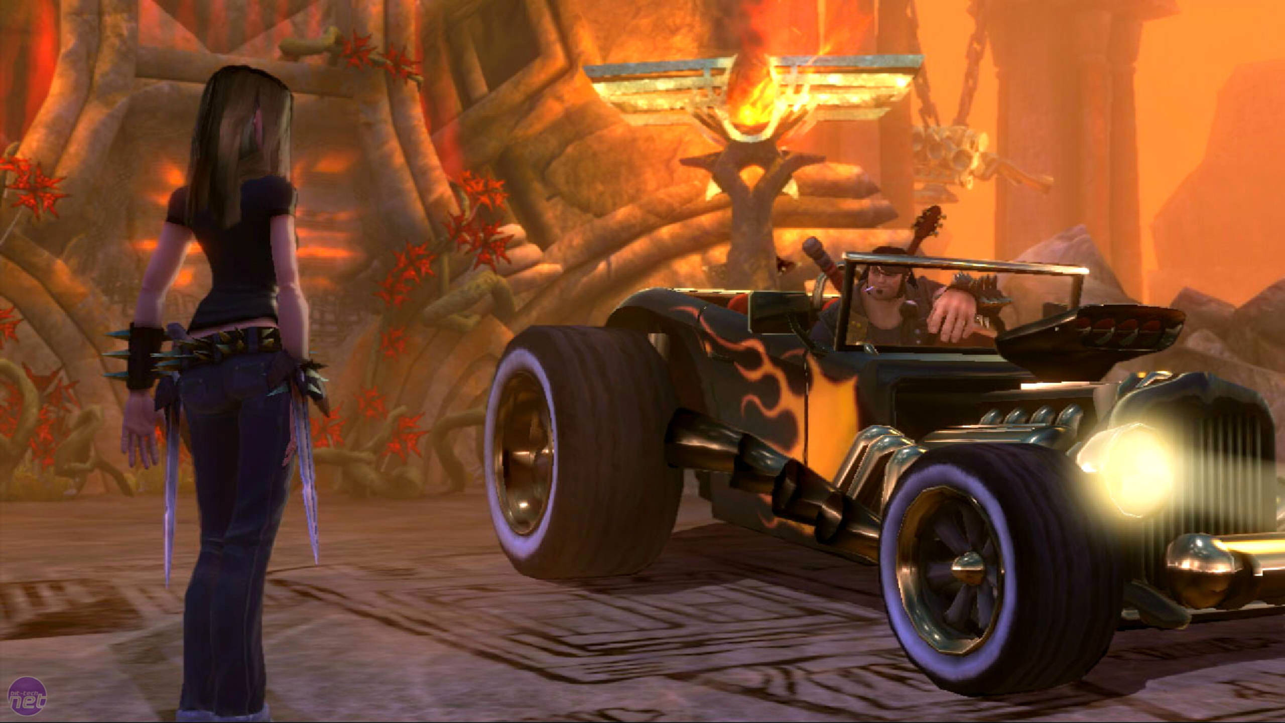 《Brutal Legend》奧菲莉亞與艾迪 壁紙 — 一名女子站在一輛燃燒的改裝車旁，身處火海廢墟中，天空泛著橙色光芒，樹木如骨架般。