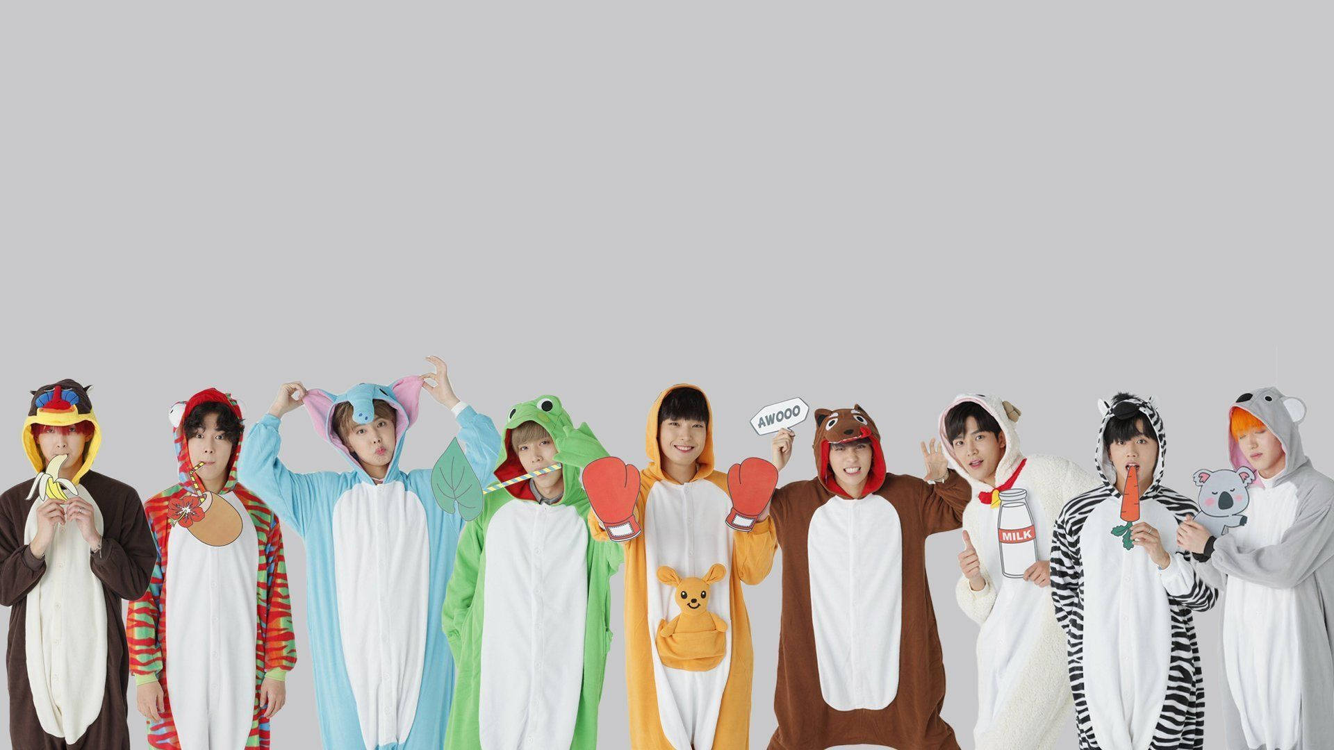 BTS 2020 可愛動物服裝 壁紙 — 七個年輕男子穿著色彩繽紛的動物連體衣，在純灰色背景前拿著道具愉快地擺姿勢。