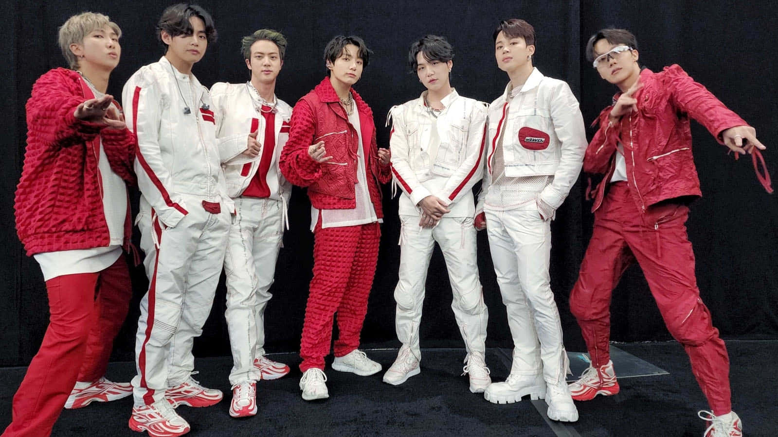 BTS 2022 Billboard Music Awards 照片 壁紙 — 七位身穿大膽紅白服裝的男性在黑色背景下以動態姿勢自信地擺姿勢。