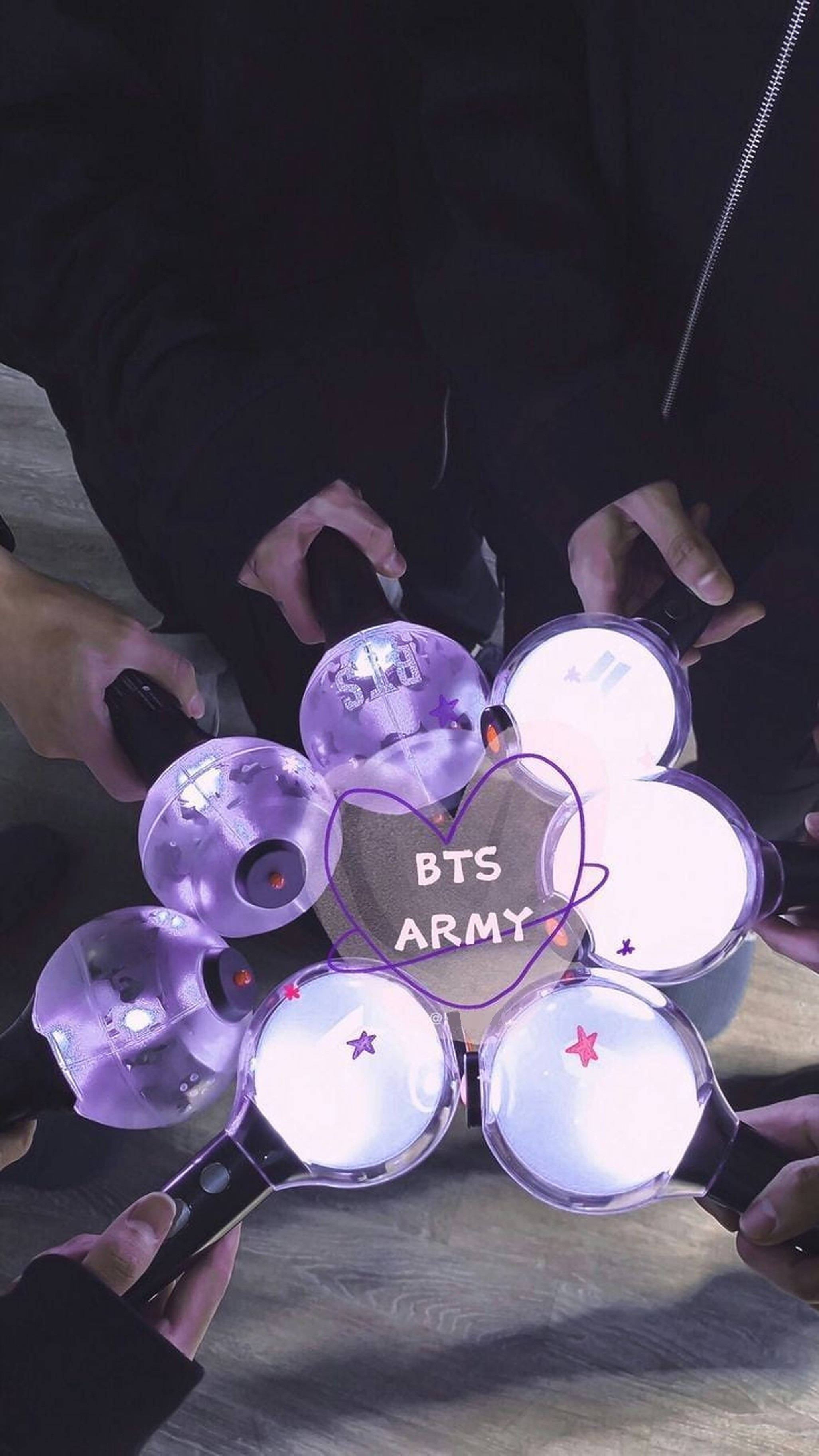 共鳴之光——BTS ARMY燈棒 壁紙 — 雙手握著發光的紫色螢光棒，圍繞著帶有BTS ARMY文字的心形形成一個圓圈。