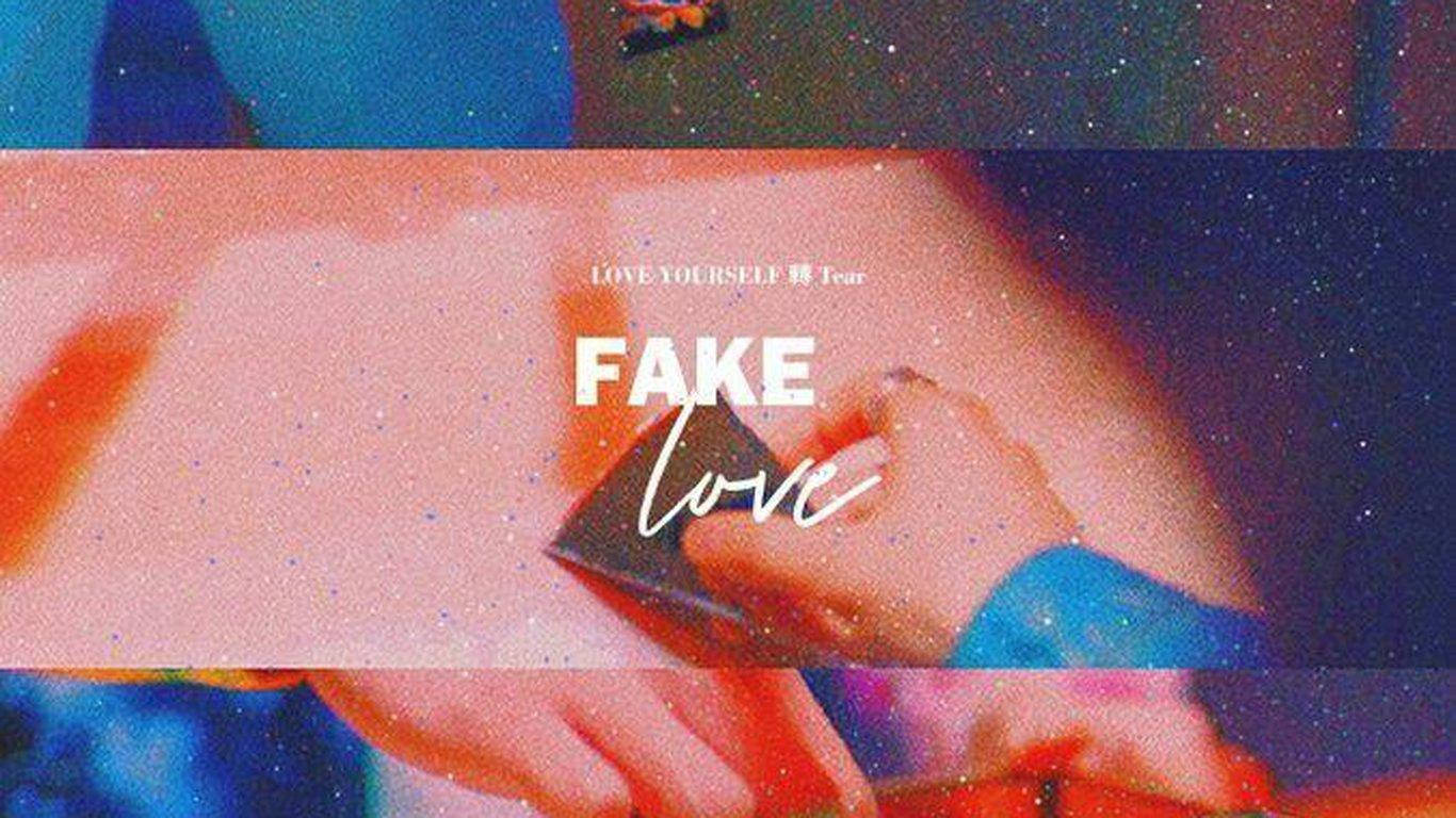 手拿著手機，在宇宙背景上顯示「FAKE love」文字。