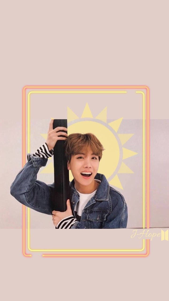 BTS J-hope 太陽 壁紙 — 一個穿著牛仔外套的開朗年輕男子，在風格化的黃色太陽背景下，手持黑色桿子，露出燦爛的笑容。