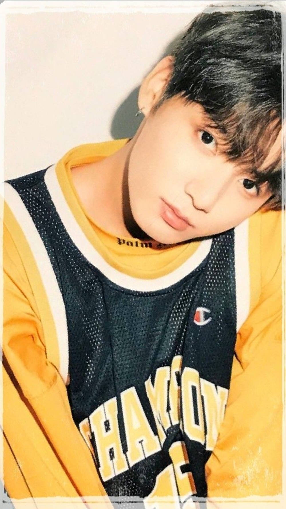 BTS JK 日本單曲專輯寫真 壁紙 — 一名黑髮年輕男子靠近鏡頭，身穿黃色和黑色Champion籃球球衣，內搭黃色襯衫。