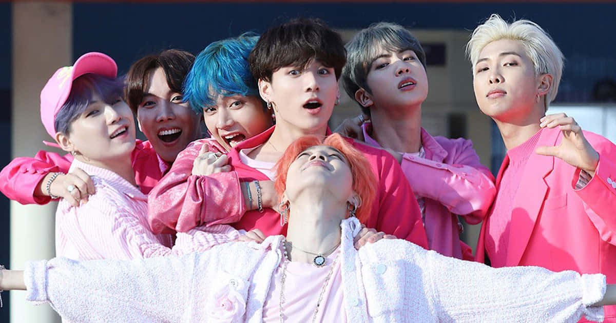 BTS - KPOP組合 - KPOP組合 - BTS - KPOP組合 - B 壁紙 — 七位年輕男子擁有鮮豔的髮色和粉紅色服裝，在明亮的日光下充滿活力地在戶外擺姿勢。