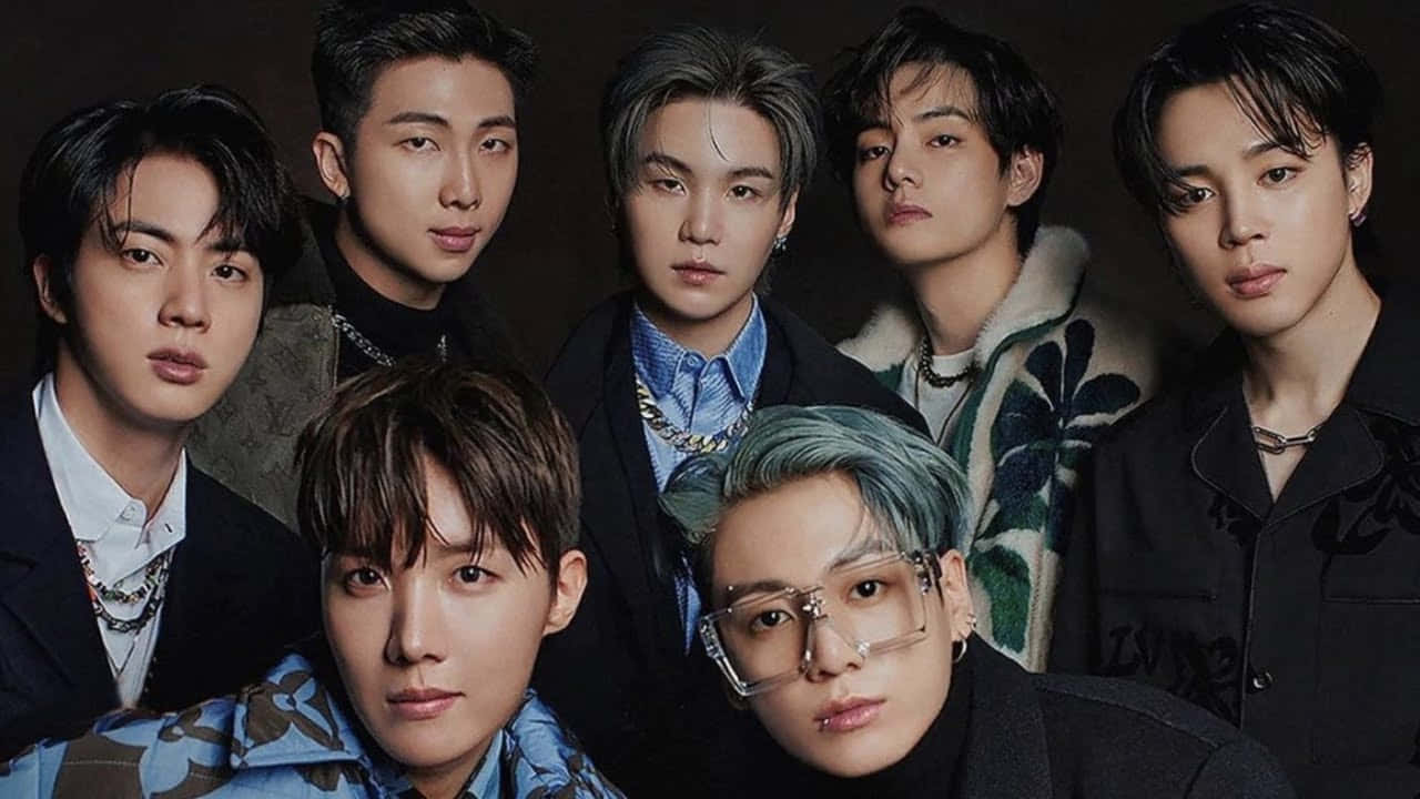 BTS《Proof》專輯封面照 壁紙 — 七位時尚的K-pop偶像在昏暗的攝影棚中自信地擺姿勢，展現大膽的時尚風格和富有表現力的眼神。