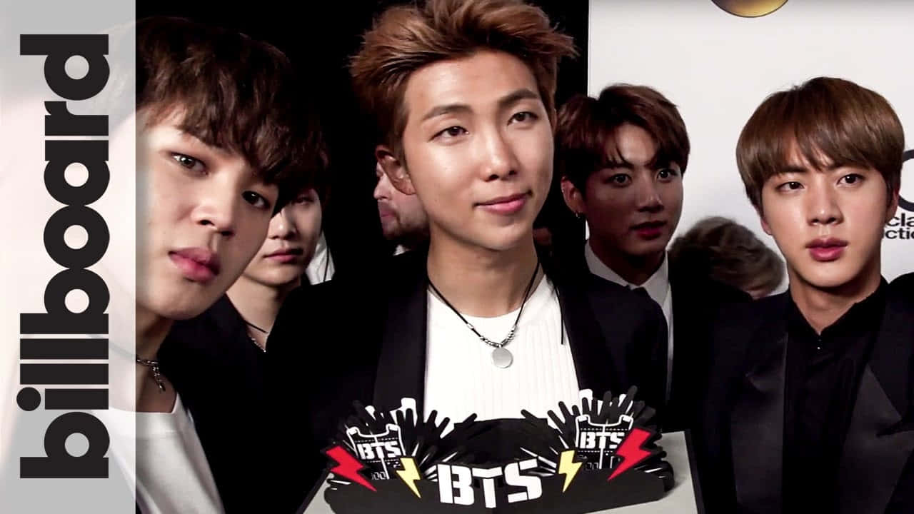 BTS RM 照片 壁紙 — 七位年輕男士穿著正裝在Billboard活動中自信地擺姿勢，前面有BTS標誌圖形。