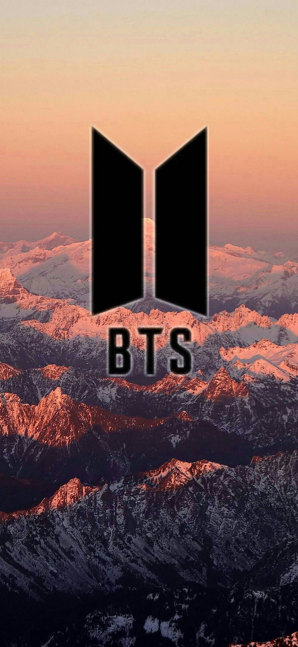BTS 標誌於美學山景 壁紙 — BTS 標誌在溫暖夕陽色調沐浴下的雪山背景中傲然矗立。