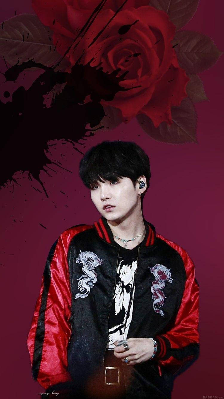 性感風 BTS Suga 壁紙 — 一位身穿紅黑 bomber 外套的年輕男子，站在深酒紅色背景前，背景有一朵大紅玫瑰和墨水飛濺。