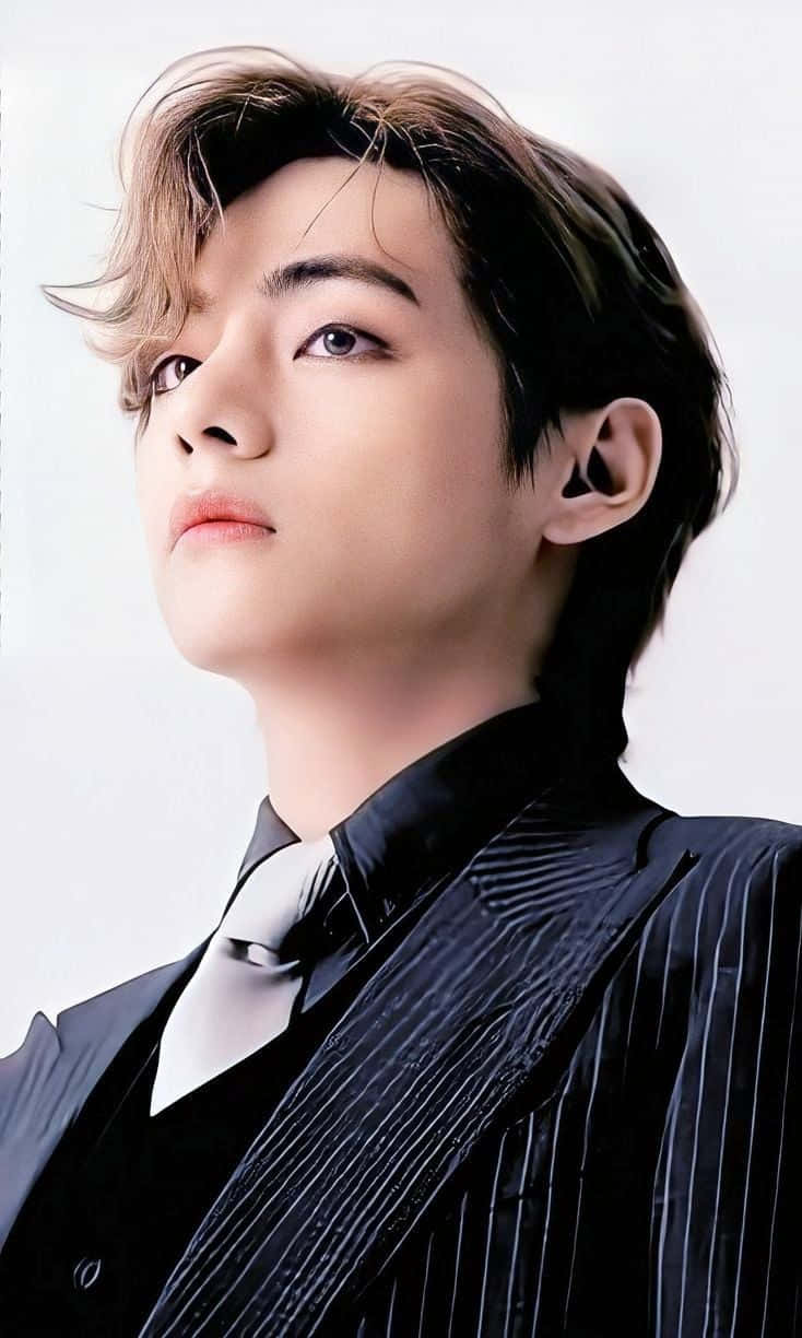 BTS V 在宣傳活動中展露溫暖笑容 壁紙 — 一位頭髮蓬鬆的年輕男子穿著時尚的黑色細條紋西裝，在純白背景前向上凝視。