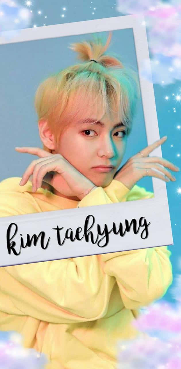 BTS V 笑容燦爛，充滿希望 壁紙 — 一位年輕男子將淺色染髮紮成高馬尾，身穿黃色連帽衫，在閃爍夢幻的天空背景下擺姿勢。