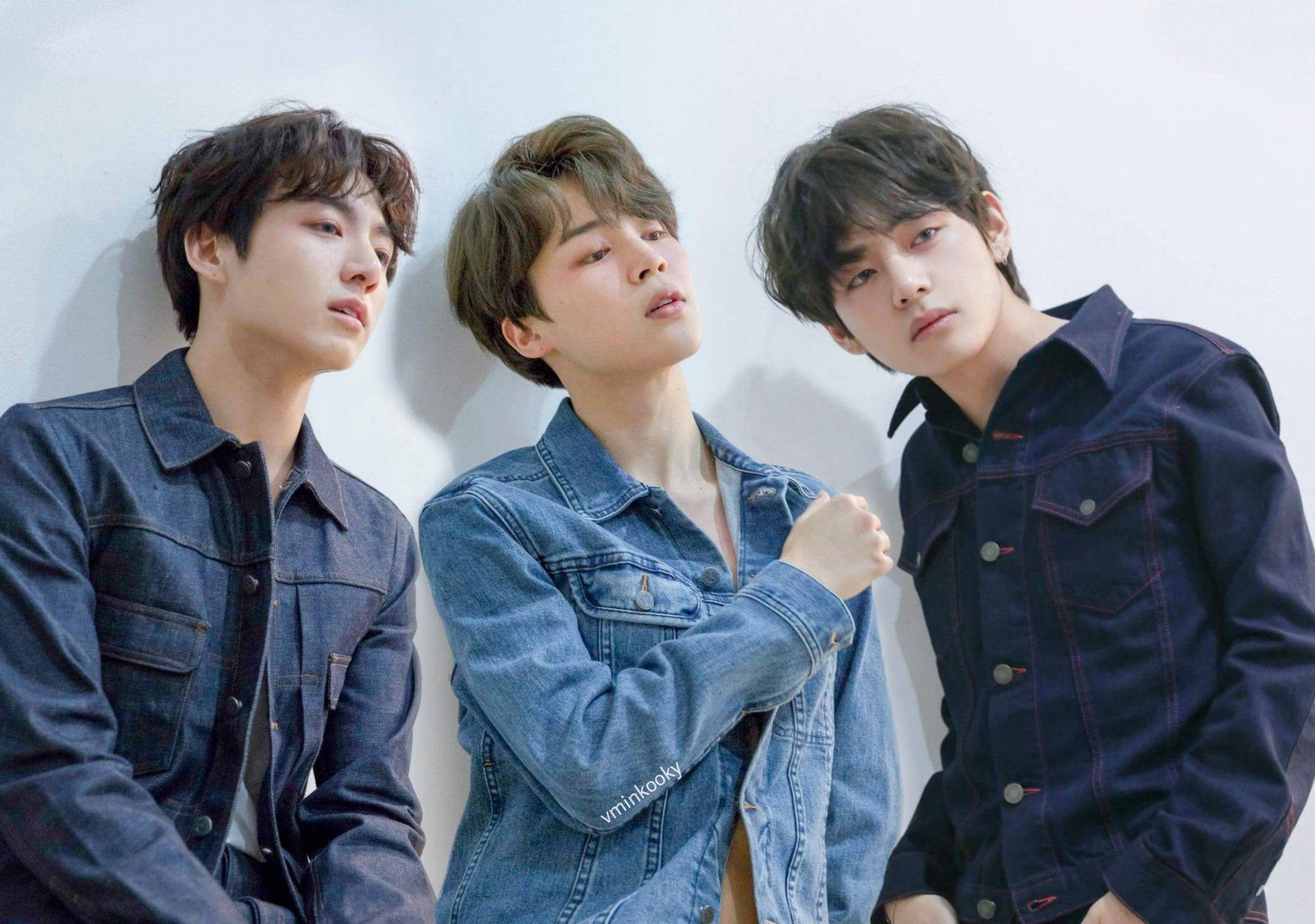 BTS V 與 Jimin（Vmin）展現深厚友誼 壁紙 — 三位年輕男子身穿牛仔外套，靠著純白牆壁，柔和的工作室燈光。