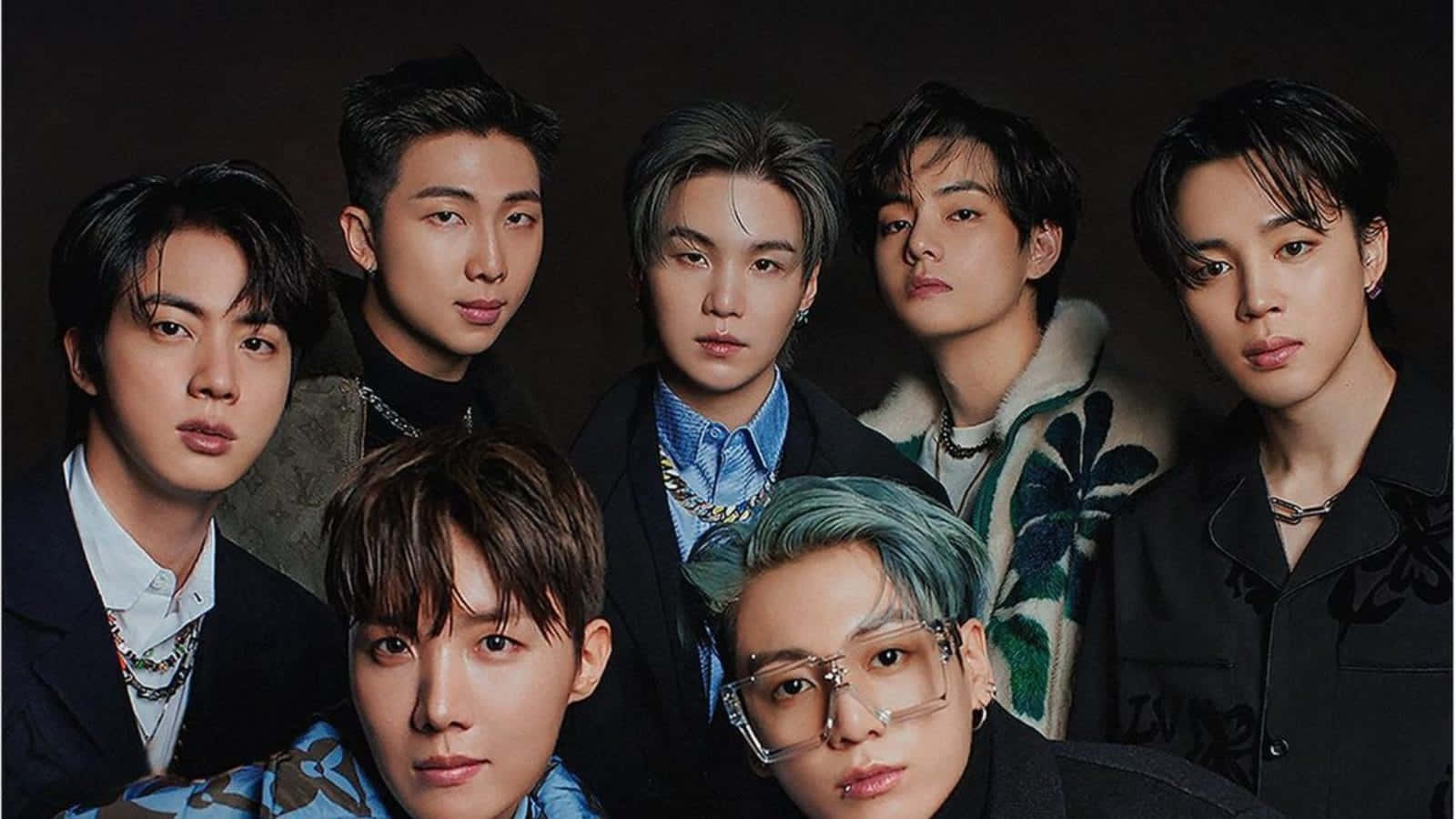 BTS《Vogue Hongkong》封面拍攝 壁紙 — 七位時尚年輕男士，擁有不同髮色和現代服裝，在深色工作室背景下自信地擺姿勢。