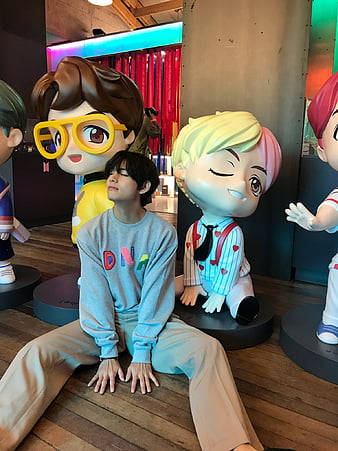 年輕男子坐在室內大型卡通雕像之間