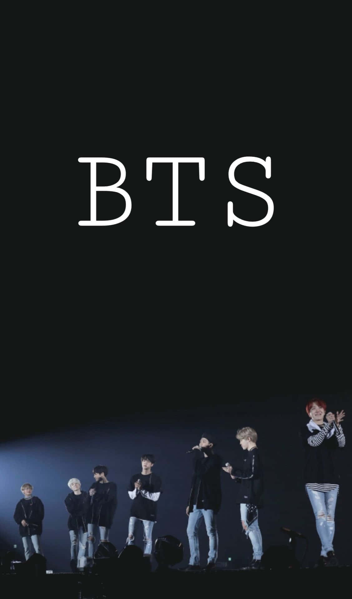 Bts Stage 桌布 壁紙 — BTS 七位成員站在燈光昏暗的舞台上，聚光燈下，上方有白色大字 BTS。