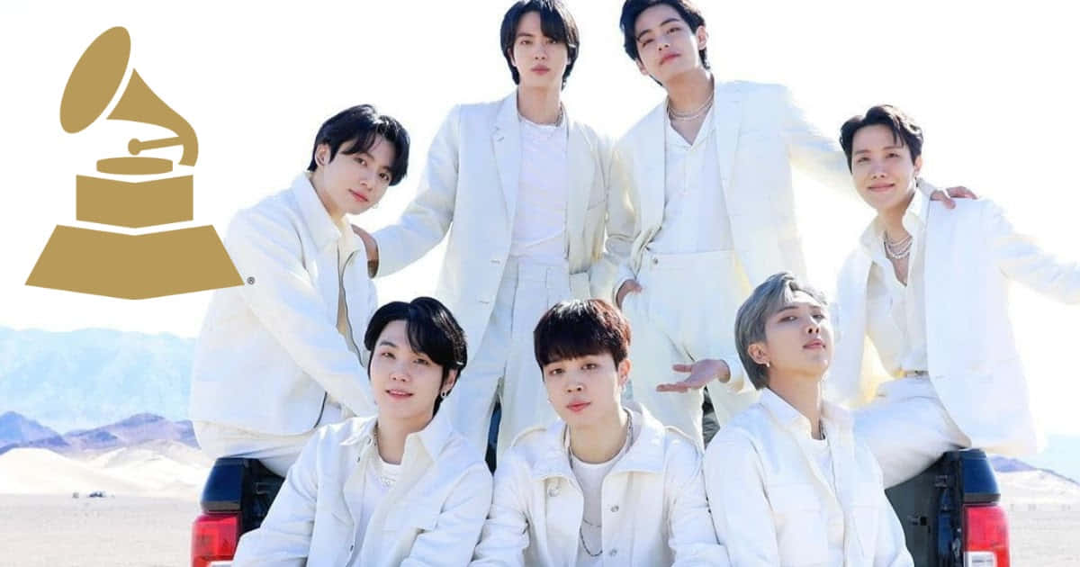 BTS 全白造型照 壁紙 — 七名身穿白色西裝的男子在沙漠景觀中的卡車上自信地擺姿勢，並帶有葛萊美獎標誌疊加。